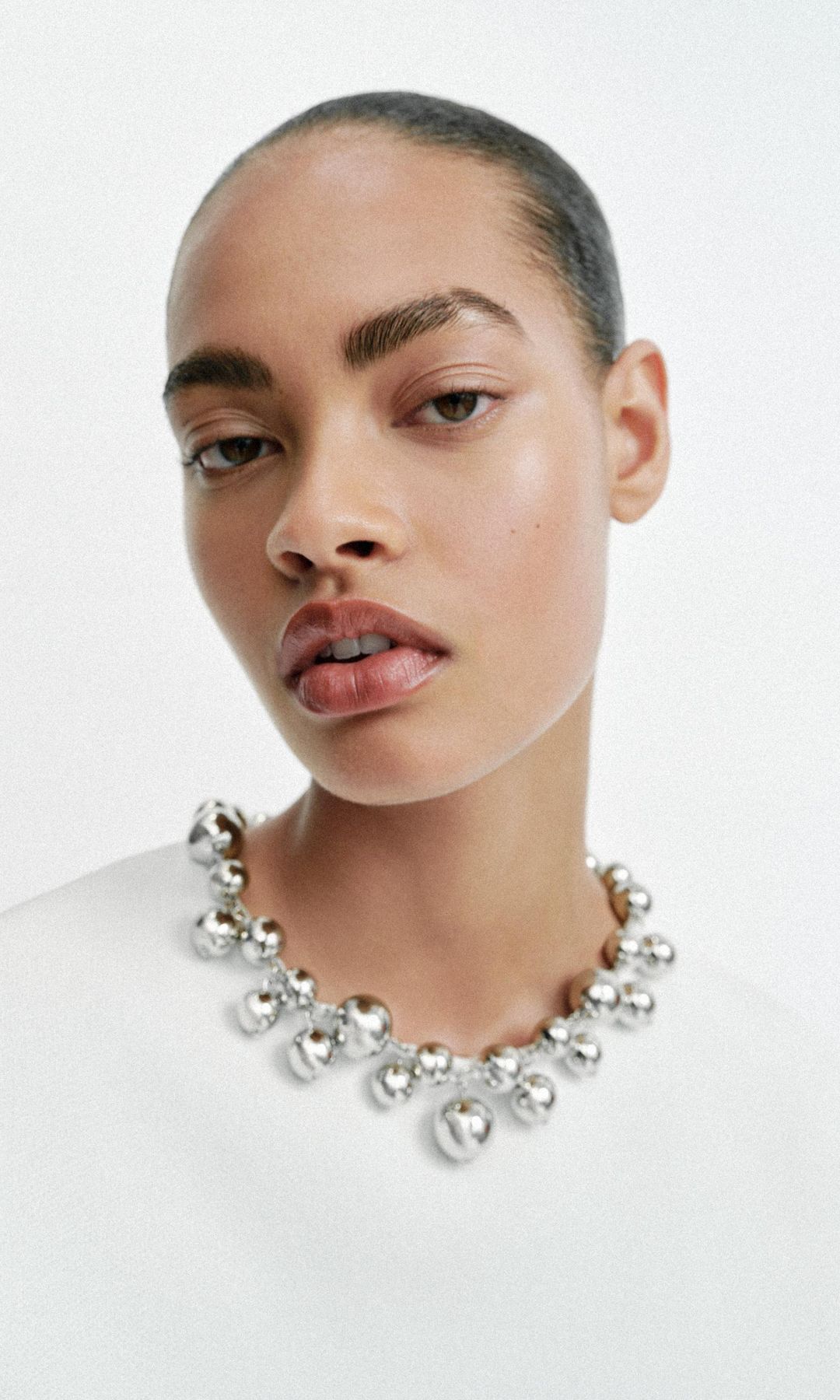 Rostro de modelo de Zara con iluminador, cejas peinadas y labios gruesos