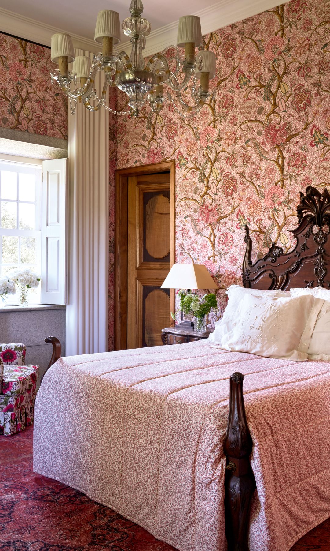Dormitorio principal con papel pintado y tejidos del sillón y de la cama de Pierre Frey. La alfombra persa es antigua y los cojines de lino, bordados con cordones y monograma bordado a mano, son piezas de familia