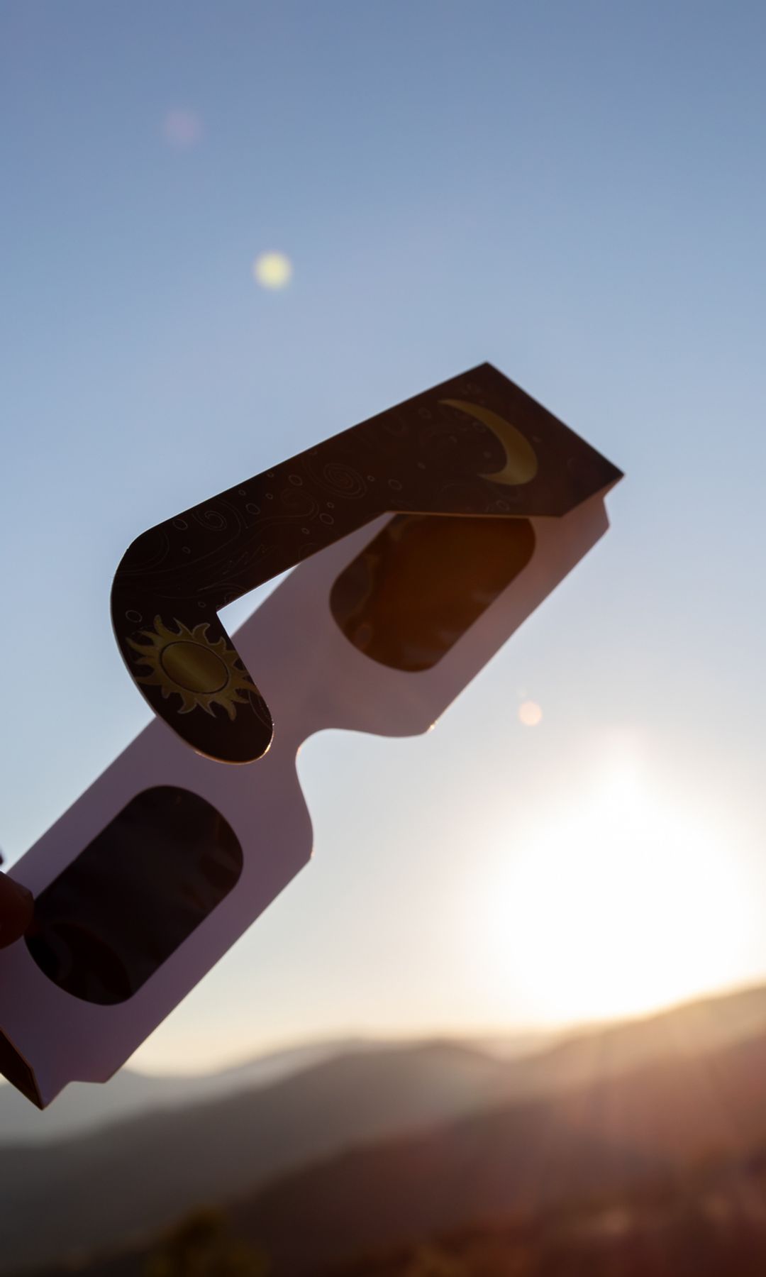manos sujetando unas gafas homologadas para ver el eclipse solar