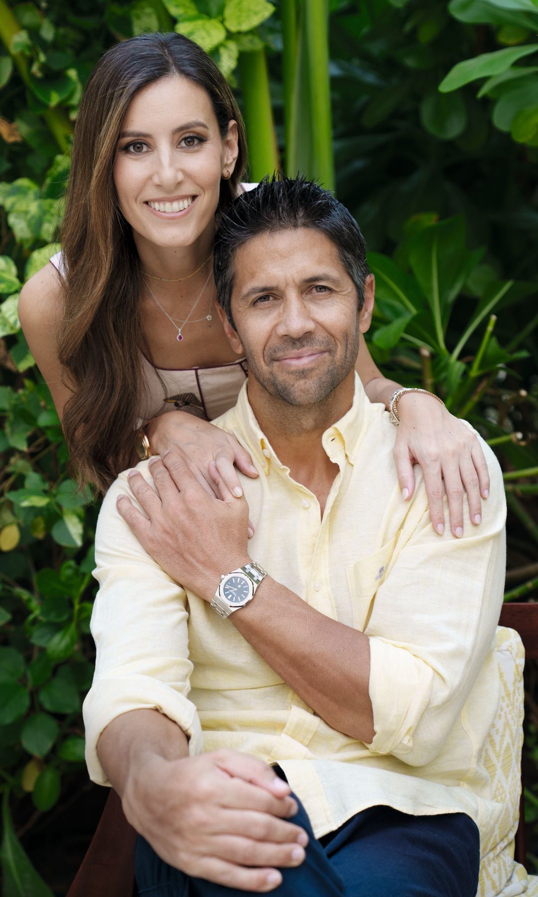 Ana Boyer y Fernando Verdasco sonrientes abrazados en un entorno natural, él c on camisa amarilla y ella con top rosa