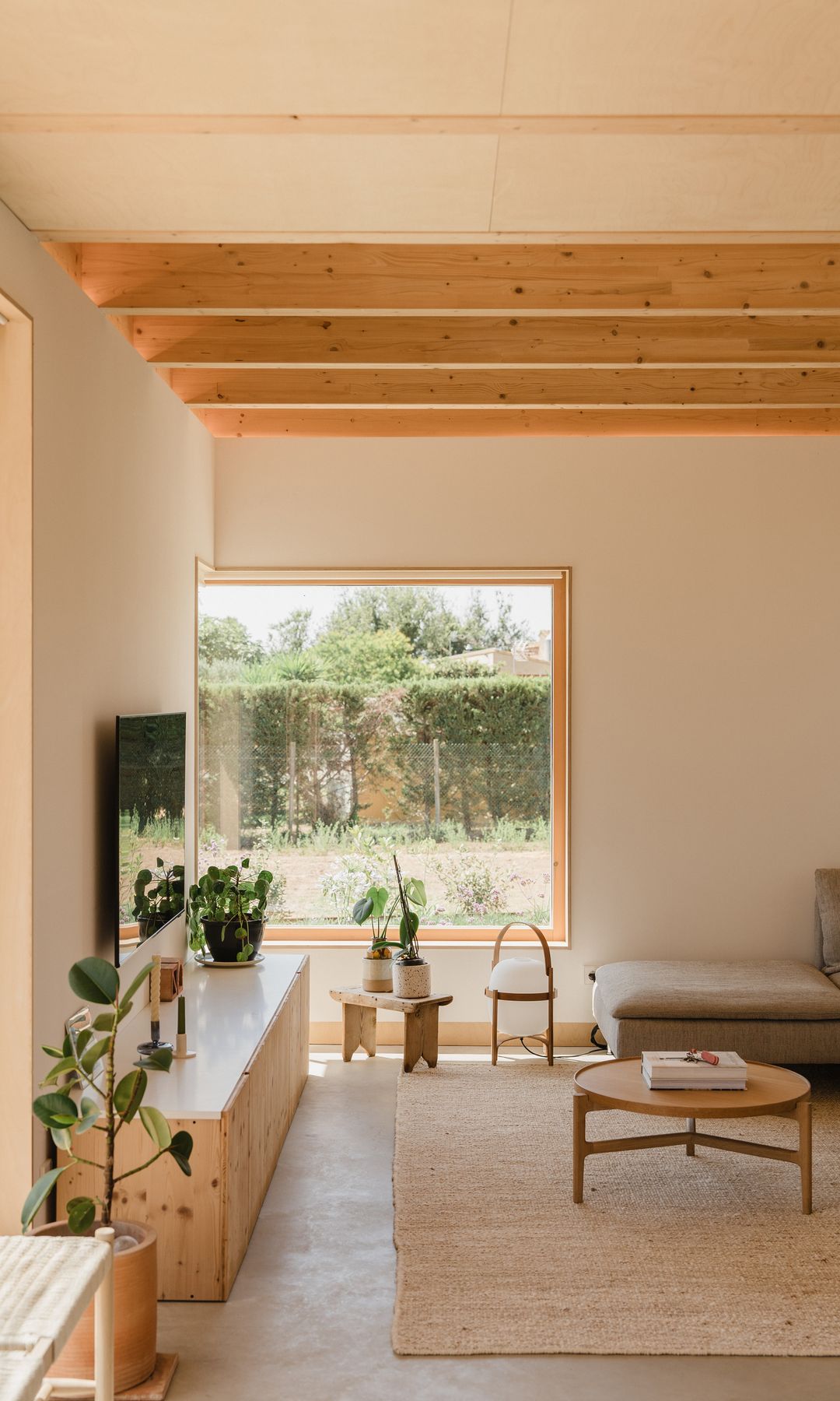 Salón con aparador bajo de madera, mueble colgada en la pared, alfombra de fibras vegetales, mesa de centro de madera, lámpara Cesta
