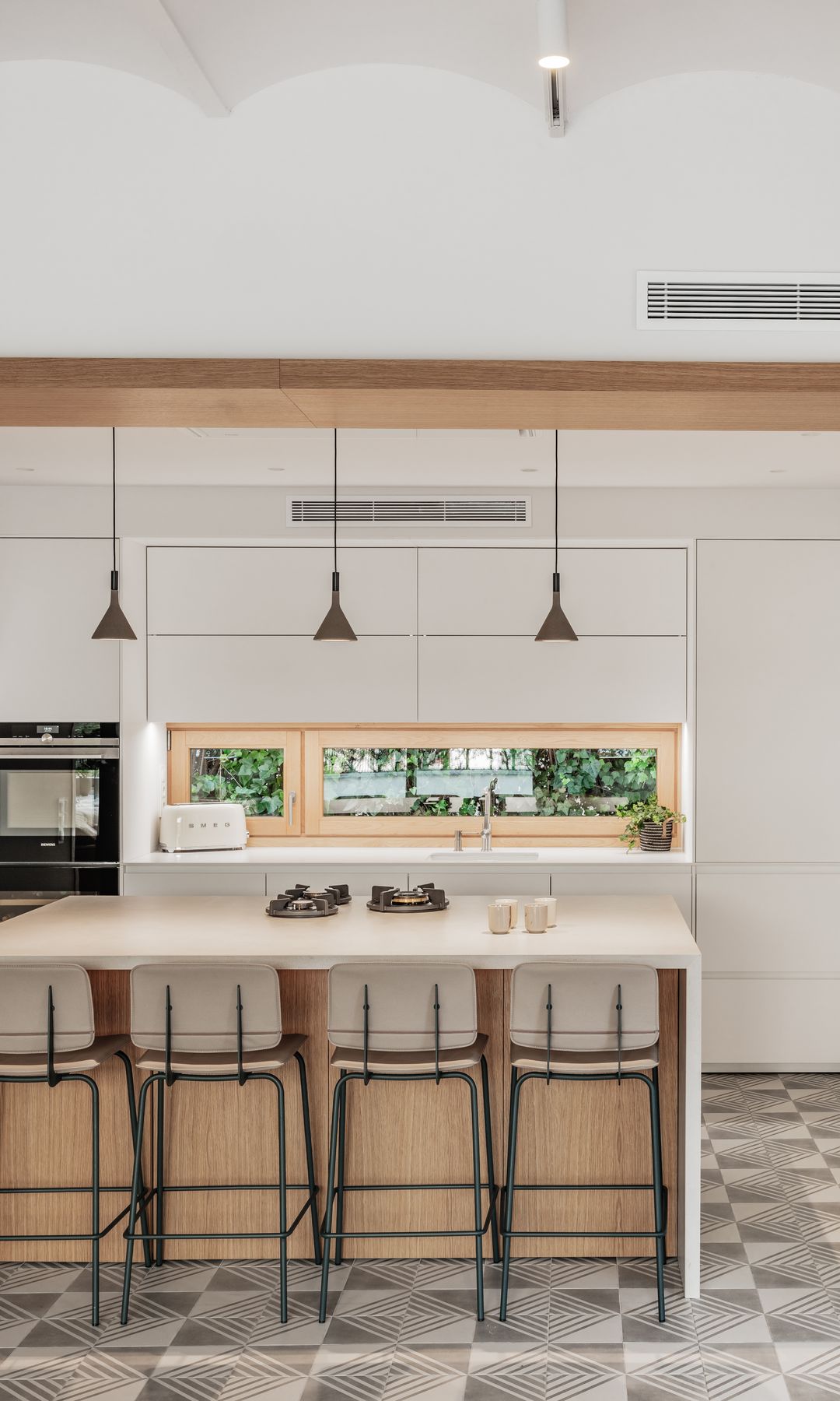 Cocina con isla con suelo de baldosas antiguas en color gris, ventana de madera, armarios blancos, ventana de madera