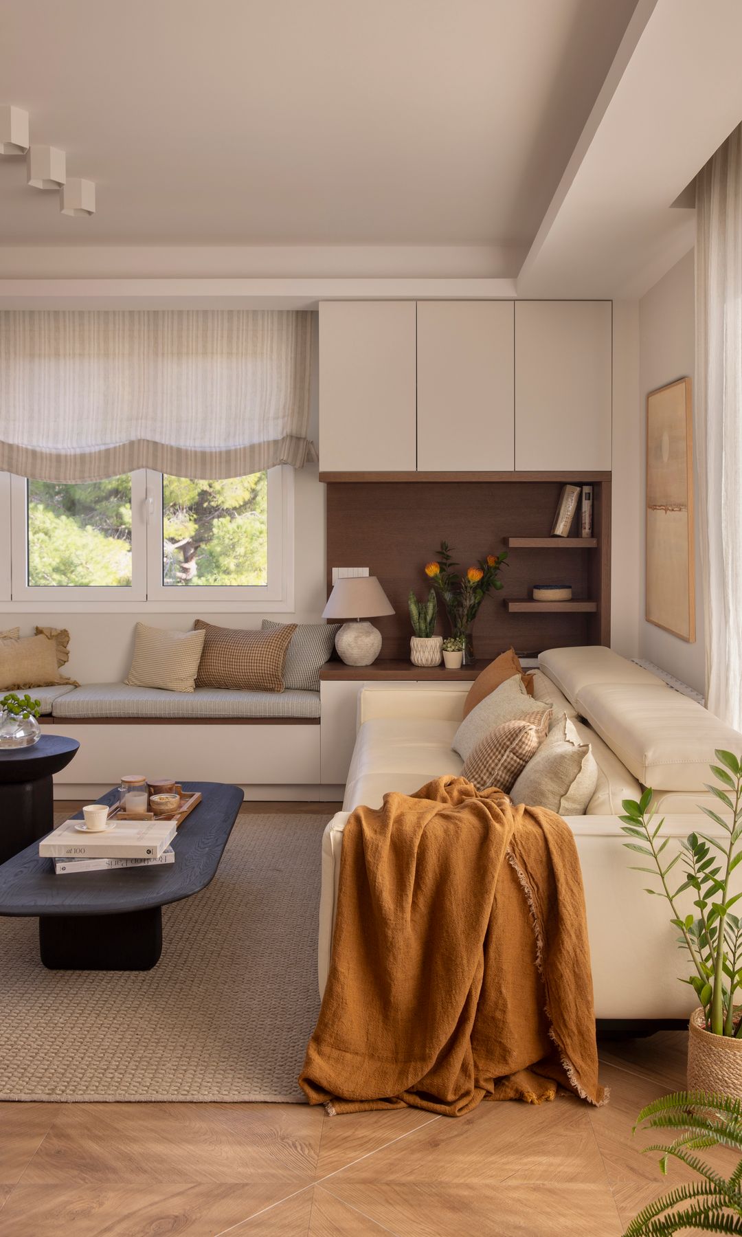 Salón con mueble a medida con banco y armarios, sofá beige, alfombra de fibras vegetales 