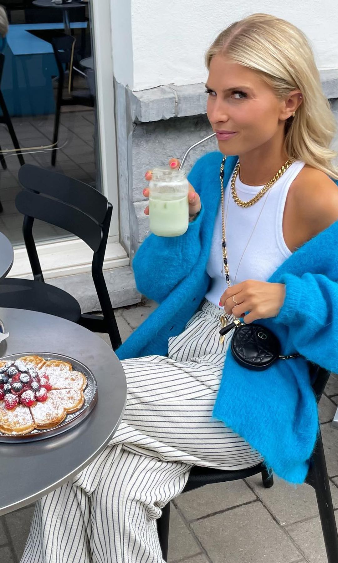 Olivia Anna-Catharina T tomando una merienda de tarta con frutos rojos llevando jersey oversized azul