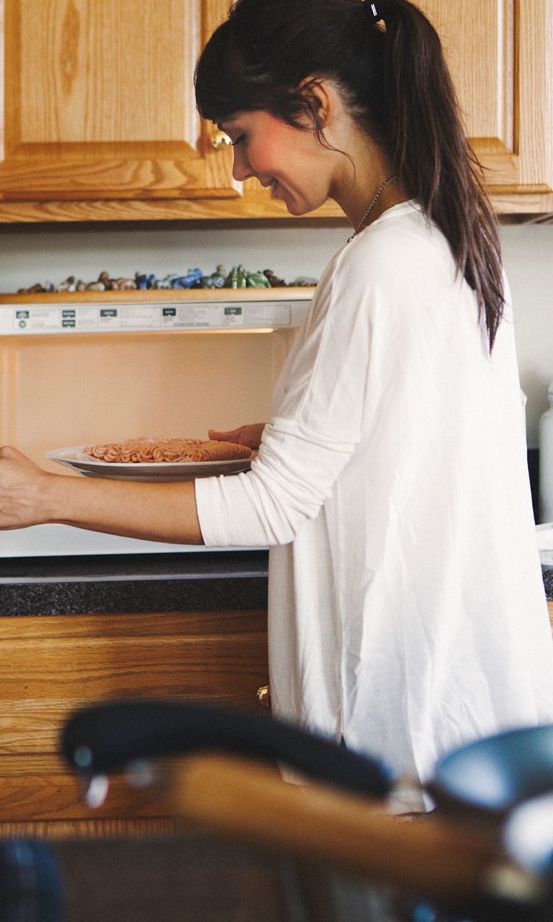 Una mujer metiendo un táper en el microondas