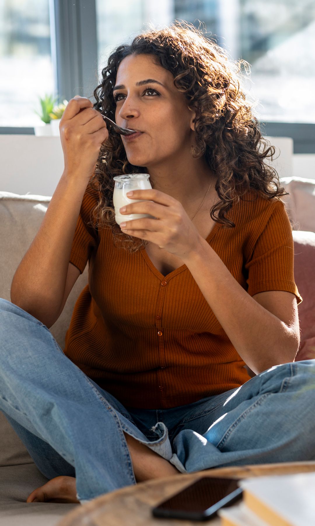 Mujer tomando un yogur en el sofá de su casa