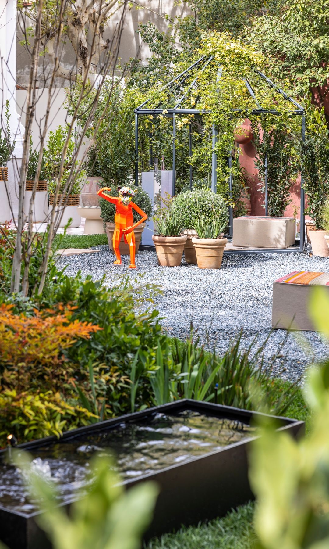 Jardín con plantas en macetas y una escultura
