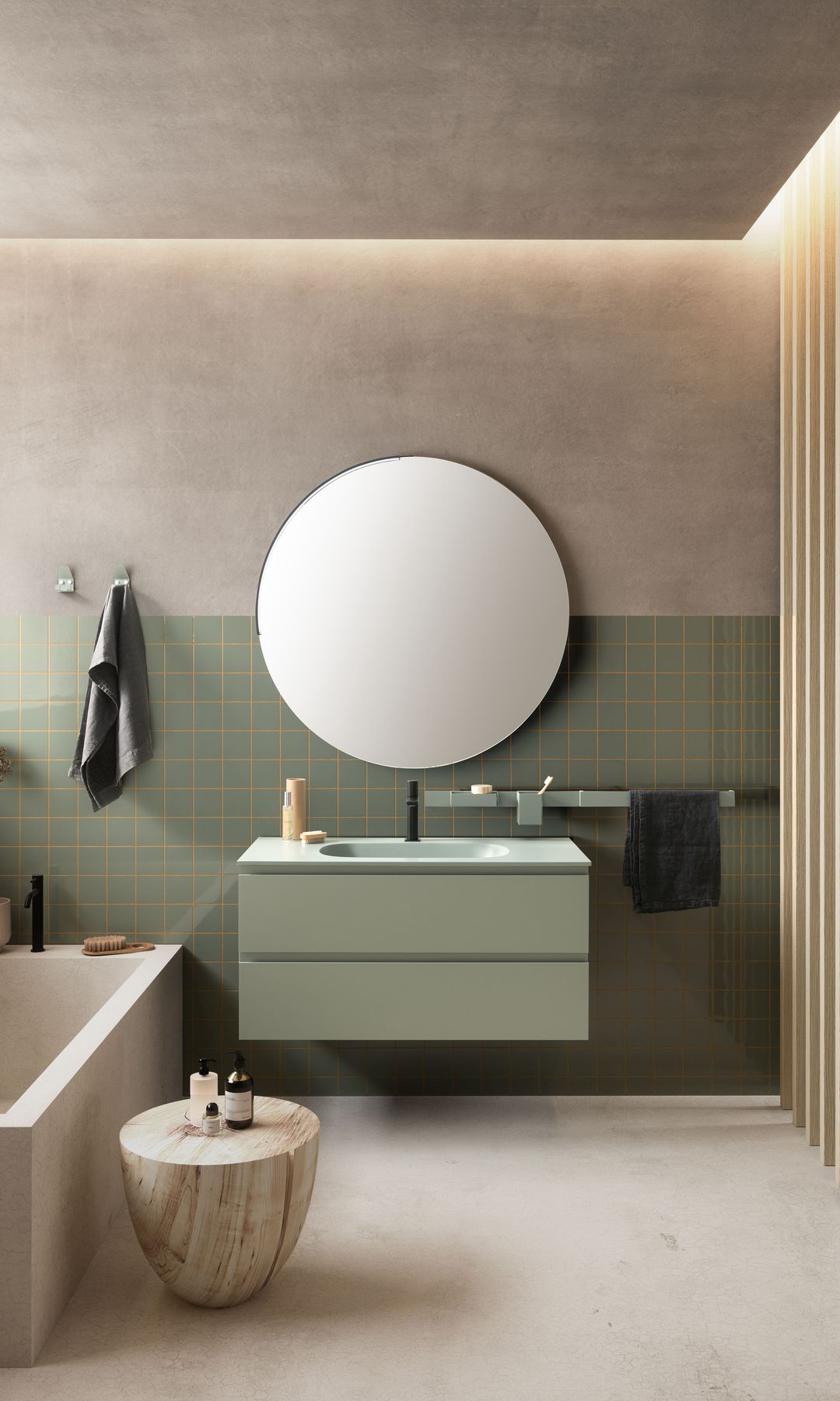 Baño con bañera, mueble bajolavabo verde oliva, pared de azulejos verdes, espejo redondo, taburete y colgadores toalla