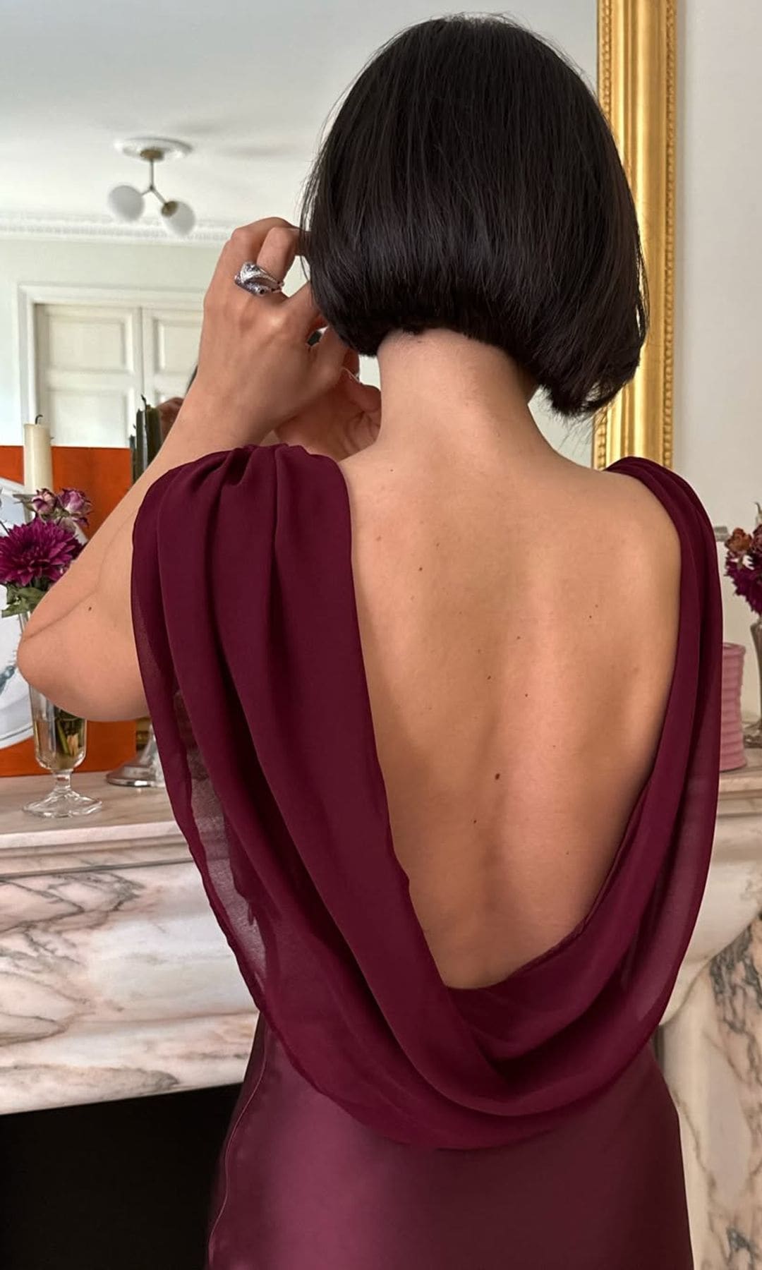 Look de invitada burdeos con capa y espalda descubierta