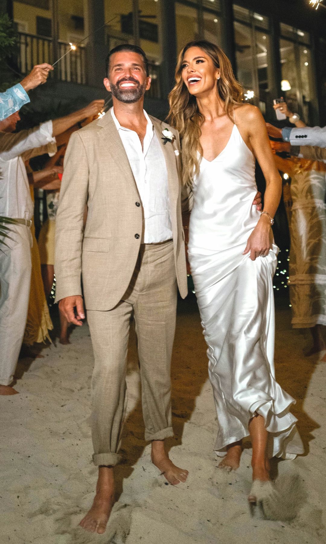 Los novios, descalzos sobre la arena en la playa, reciben las felicitaciones de sus invitados