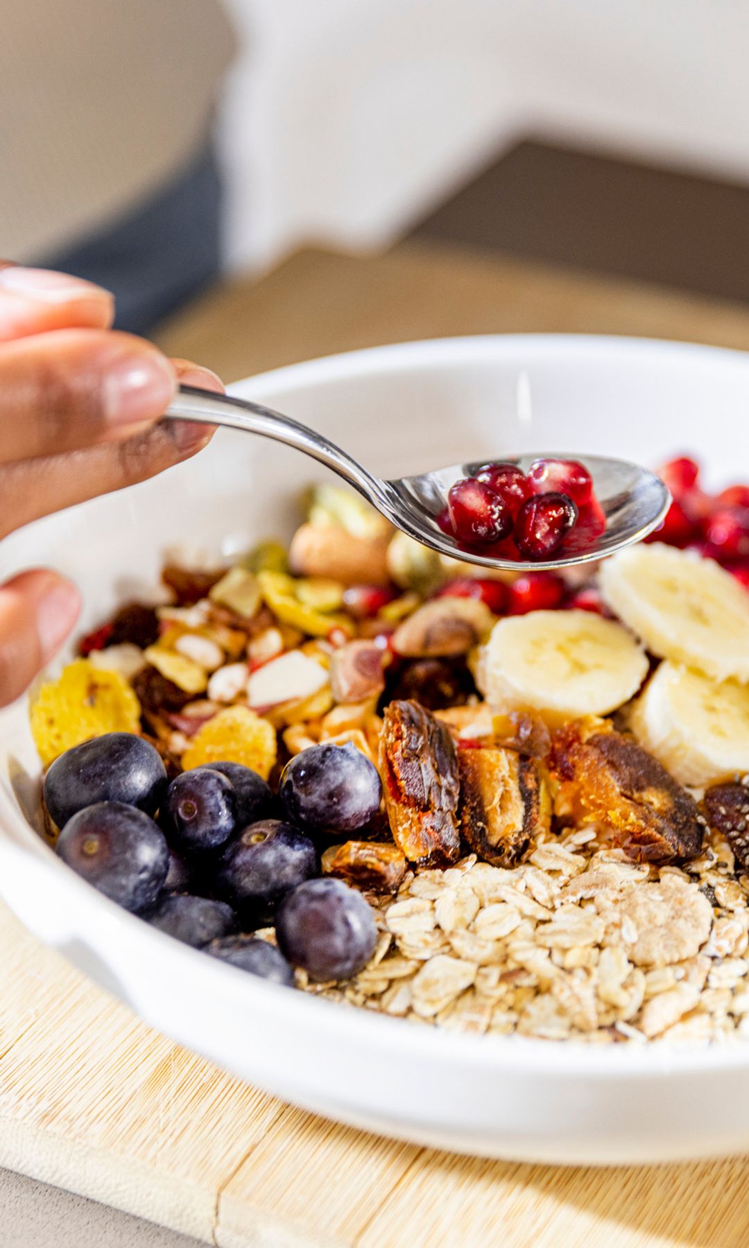 Bol de desayuno con avena, fruta fresca, semillas y frutos secos sobre una tabla de madera
