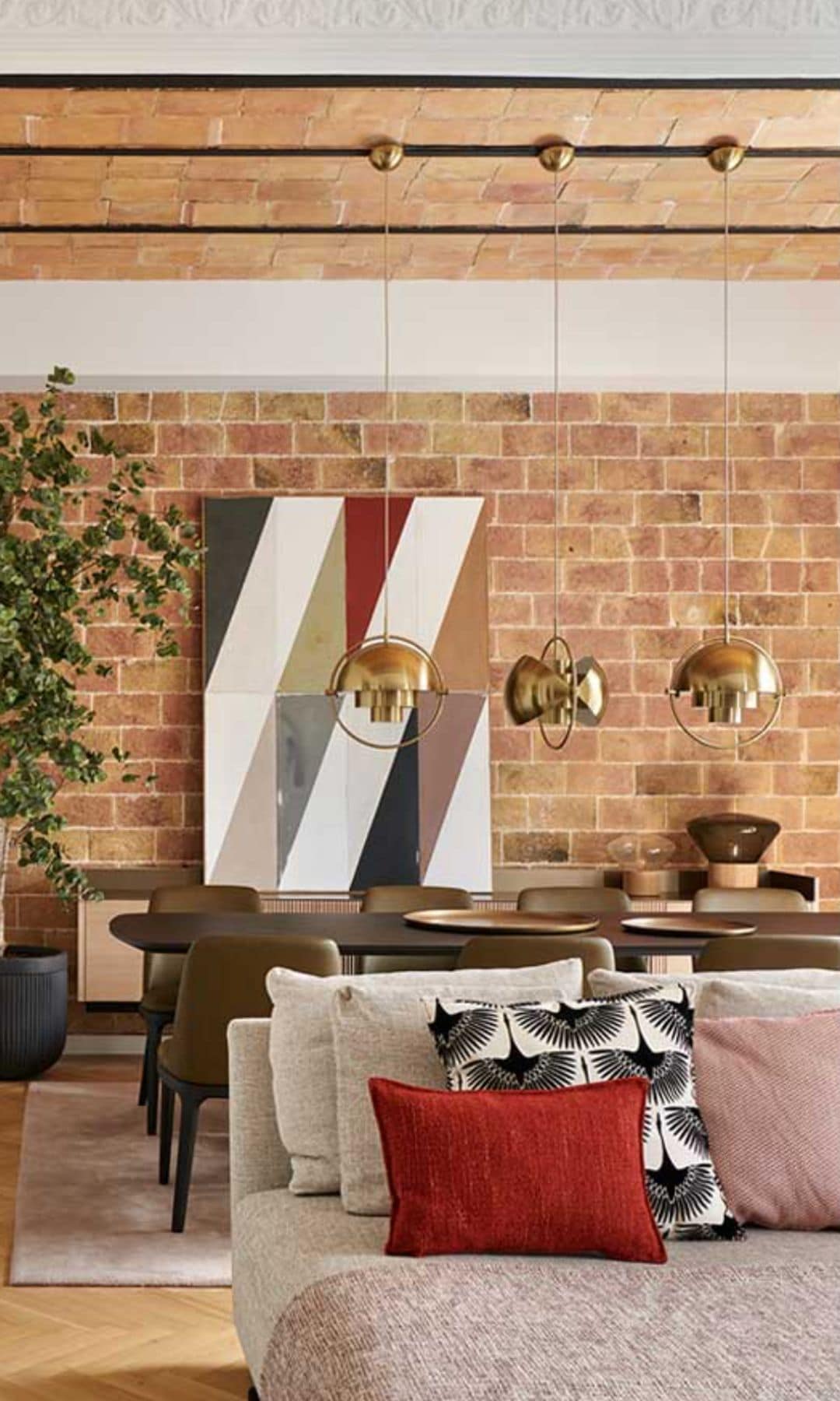 Salón comedor con pared de ladrillo, bóvedas catalanas en el techo, lámparas de techo doradas, puerta corredera