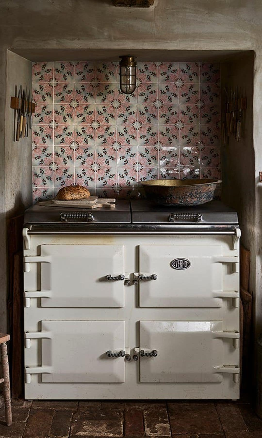 Cocina antigua de gas con pared de azulejos rosas y blancos