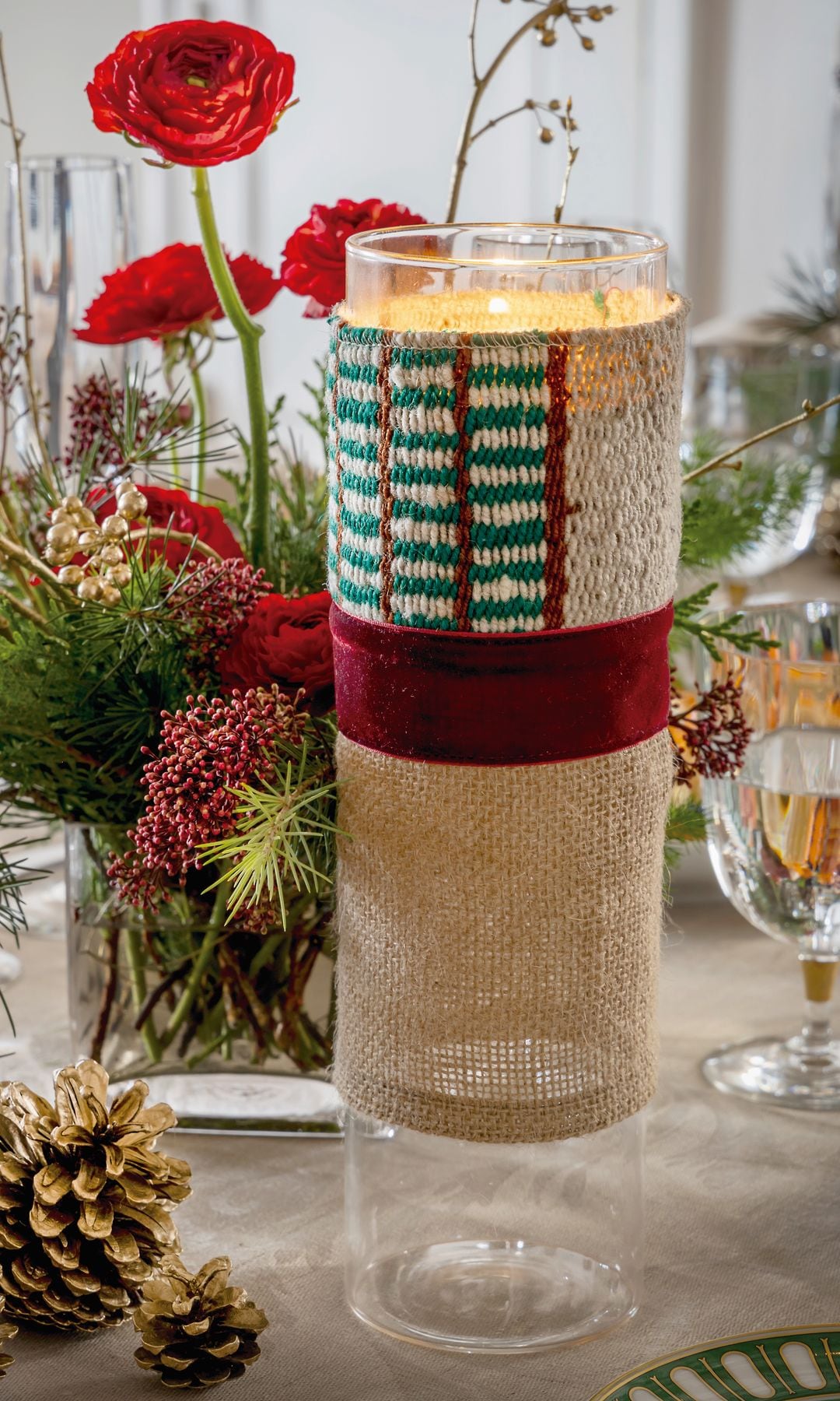 Mesa de navidad con portavelas forrado con yute, centro de flores, copas y piñas