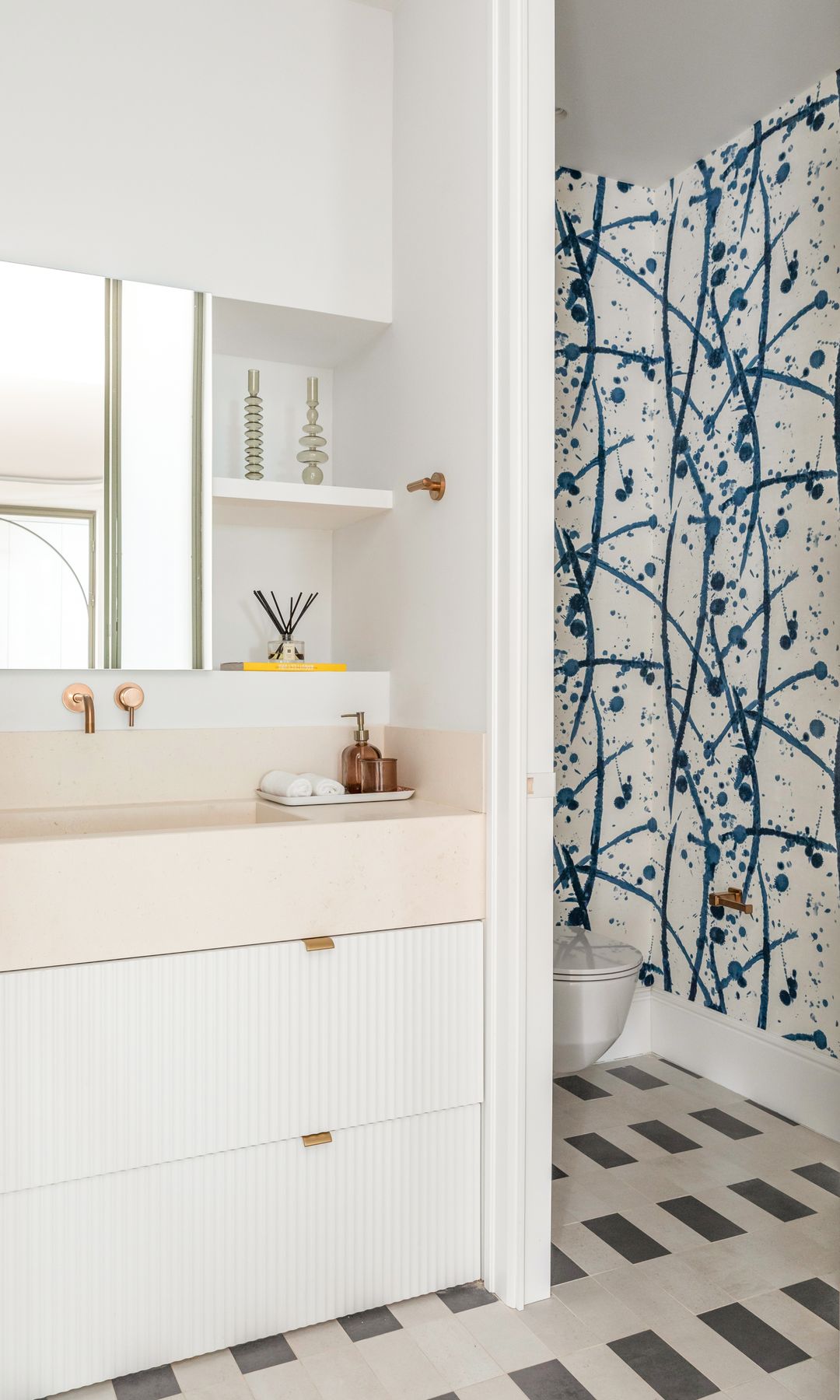Baño en blanco con suelo porcelánico, papel pintado en la zona del sanitario 