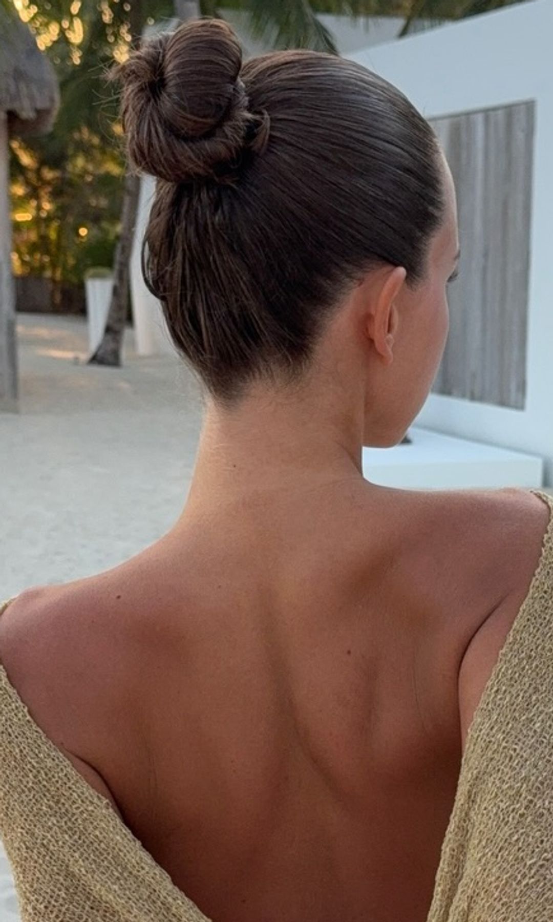 Isabelle Mathers de espaldas con moño alto y pareo dorado