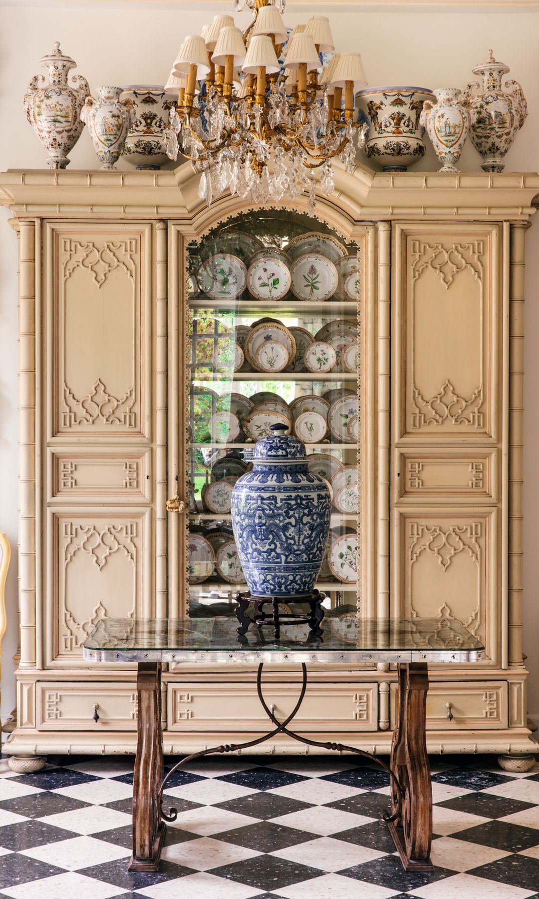 Sala con vitrina antigua, vajilla, jarrón azul y blanco, y candelabro de cristal.