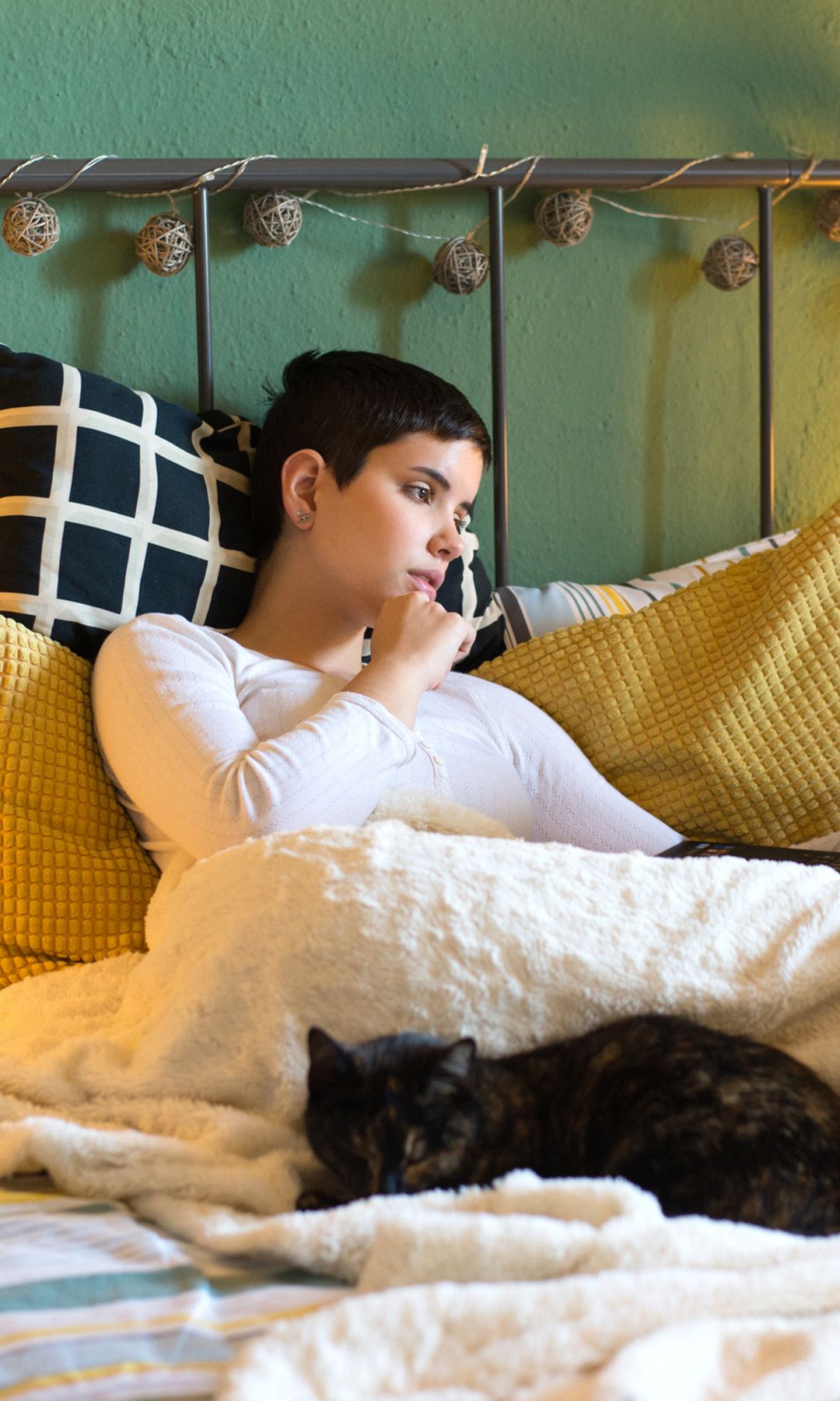 Mujer joven leyendo con gato en la cama
