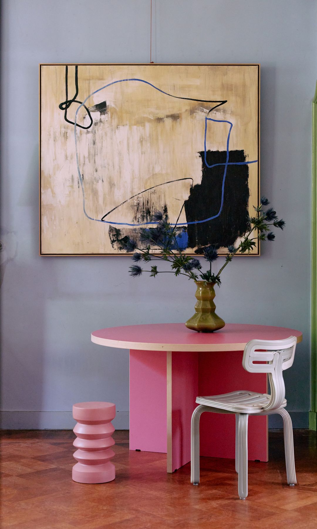 Mesa de comedor de color rosa con cuadro amarillo, paredes lila, taburete rosa y silla metálica lila