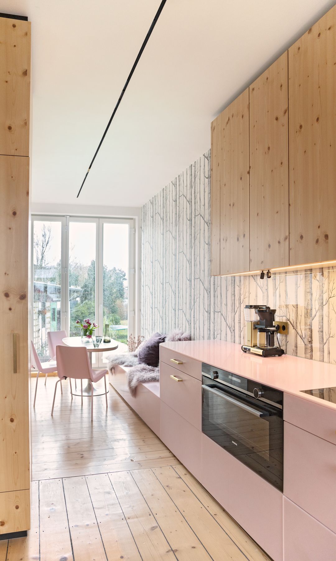 Cocina con muebles superiores de madera y muebles inferiores y encimera de color rosa claro, suelo de madera 