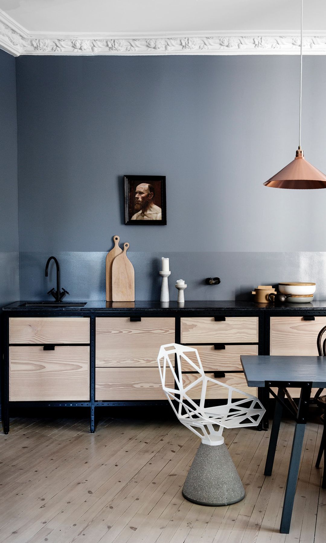 Cocina con comedor con paredes en color gris, muebles de madera, lámpara de techo, silla escultura en blanco y gris