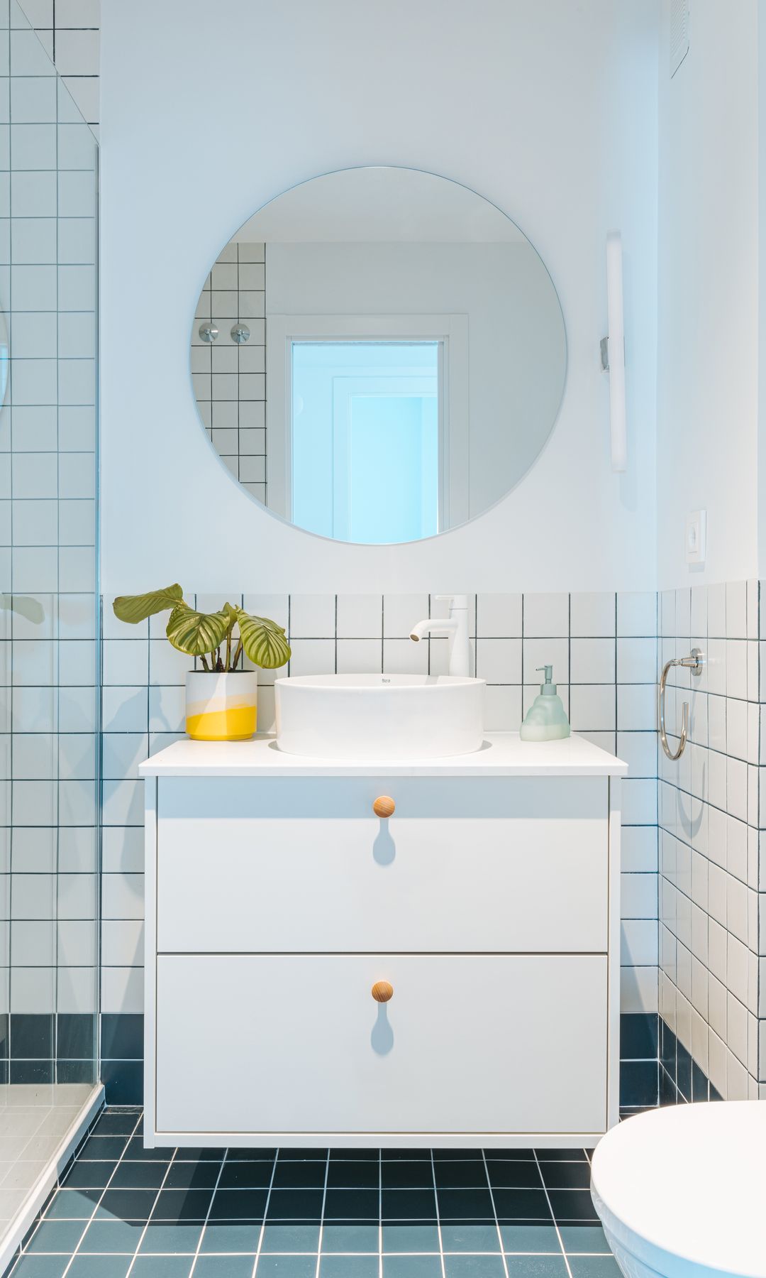 Baño con zócalos de azulejos blancos con la junta azul y suelo de azulejos azules con la junta blanca 
