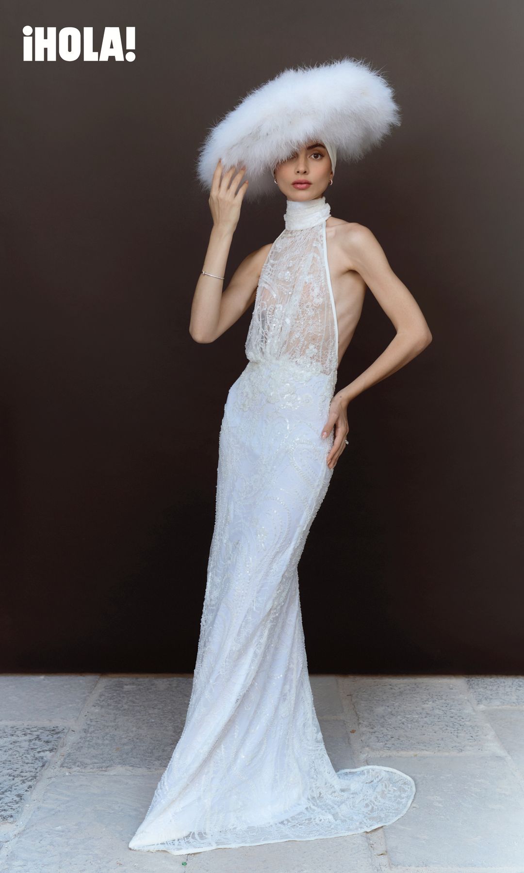  En esta imagen, la novia luce un vestido de Alfredo Martínez y un sombrero de plumas de Step On Fashion. Completa el estilismo con solitario Tiffany Novo®, brazaletes Lock Narrow y T T1, y aretes Knot de Tiffany & Co. 