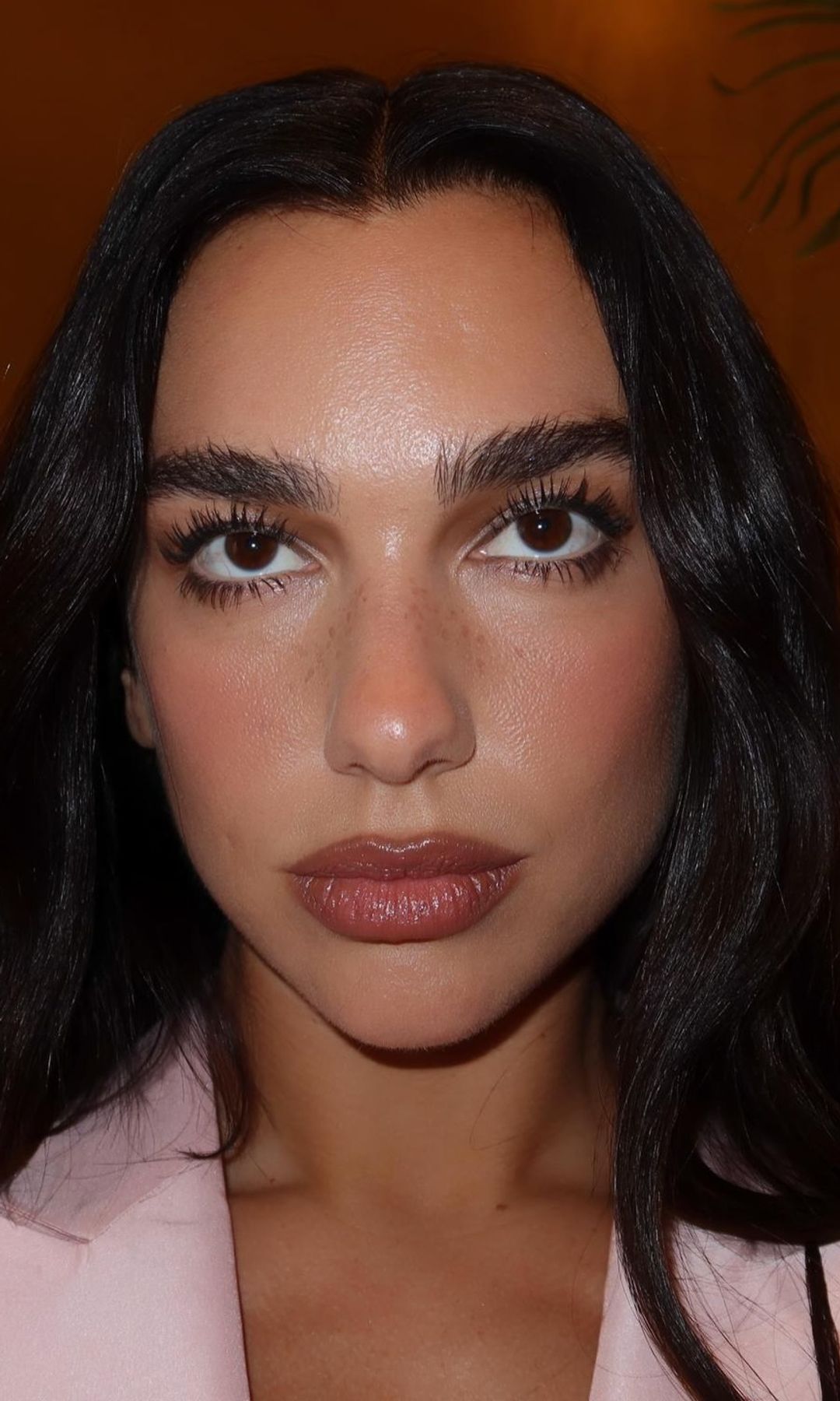 Rostro de Dua Lipa con máscara de pestañas, cejas peinadas y labios maquillados