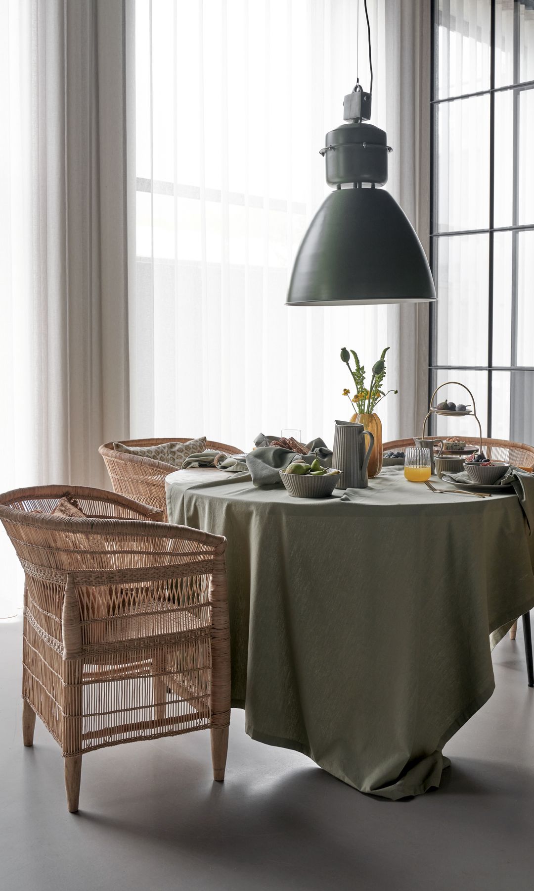 Comedor con mantel y sillones de fibras vegetales, lámpara de techo de estilo industrial