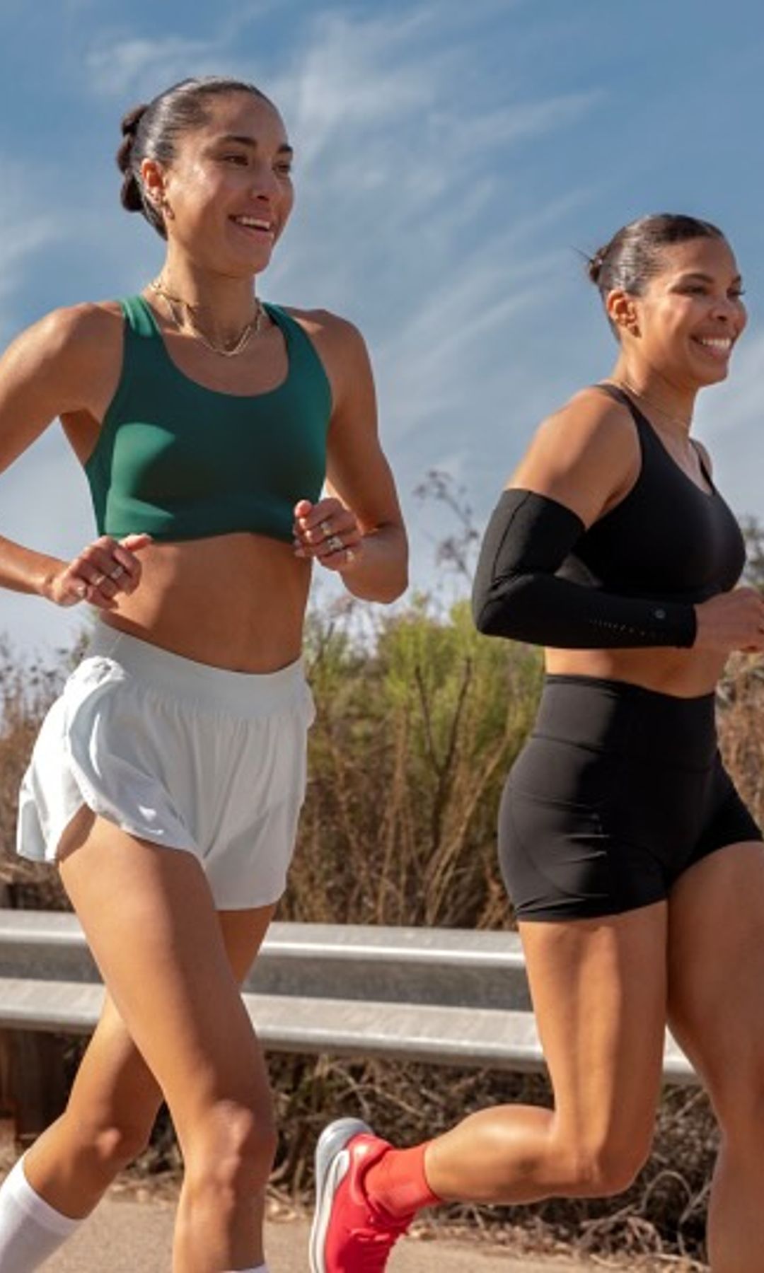 Dos mujeres corriendo en la carretera, una en verde y otra en negro.