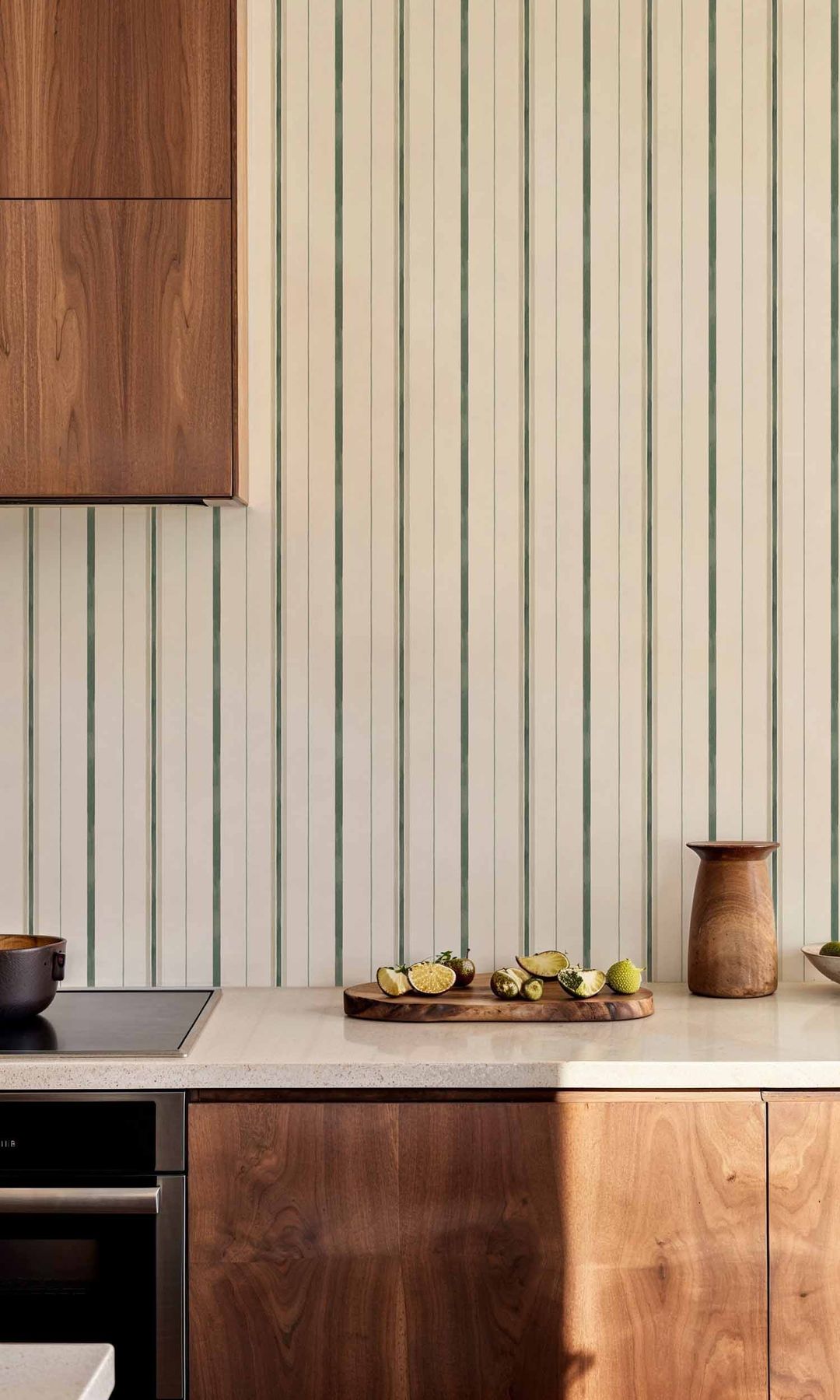 Cocina con muebles de madera, encimera blanca y papel pintado de rayas blancas y verdes