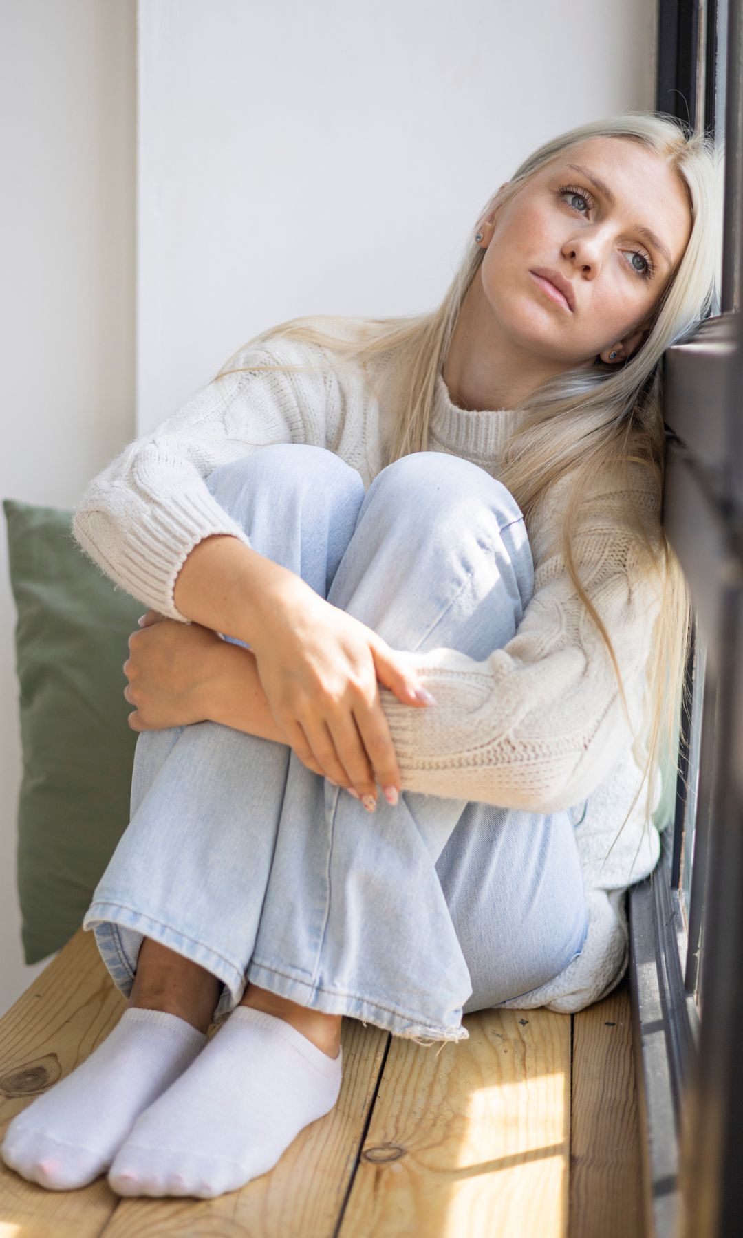 Mujer triste apoyada en una ventana