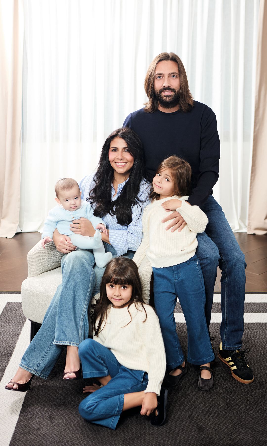 Sara Verdasco y Juan Carmona posando para una foto en un sofá, con cortinas blancas al fondo