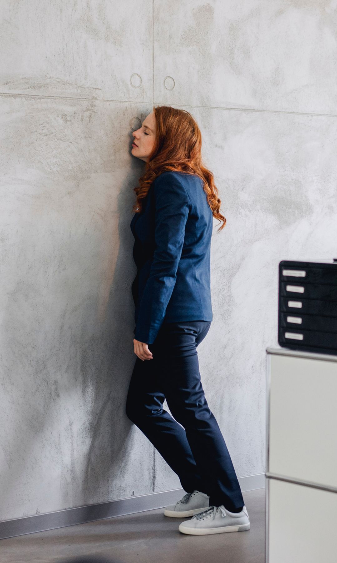 mujer cansada apoyando su cabeza en la pared