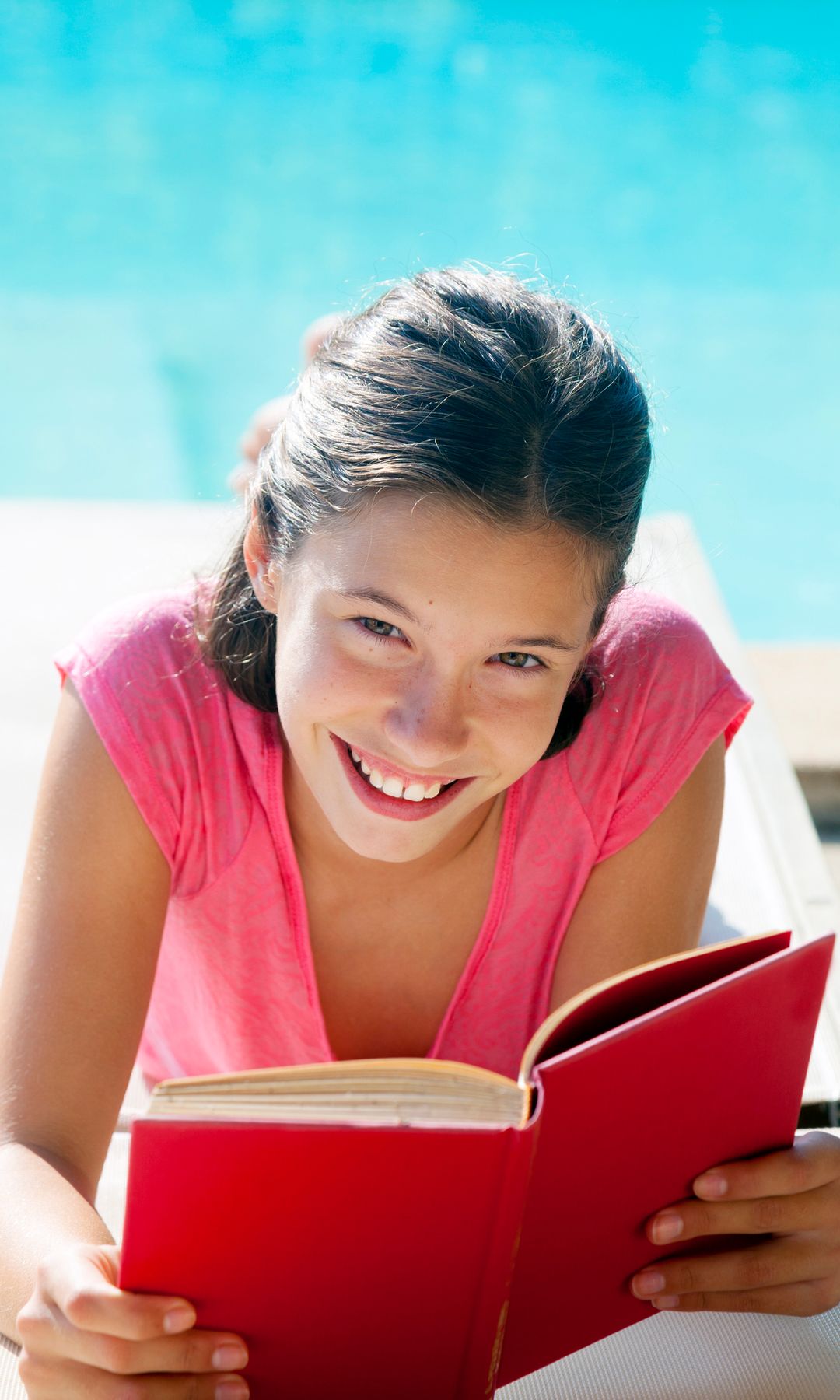 Niña leyendo contenta en la piscina