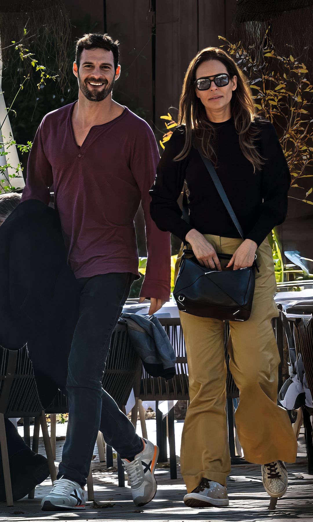 Eva González y Nacho Llanos caminan juntos en terraza de restaurante al aire libre