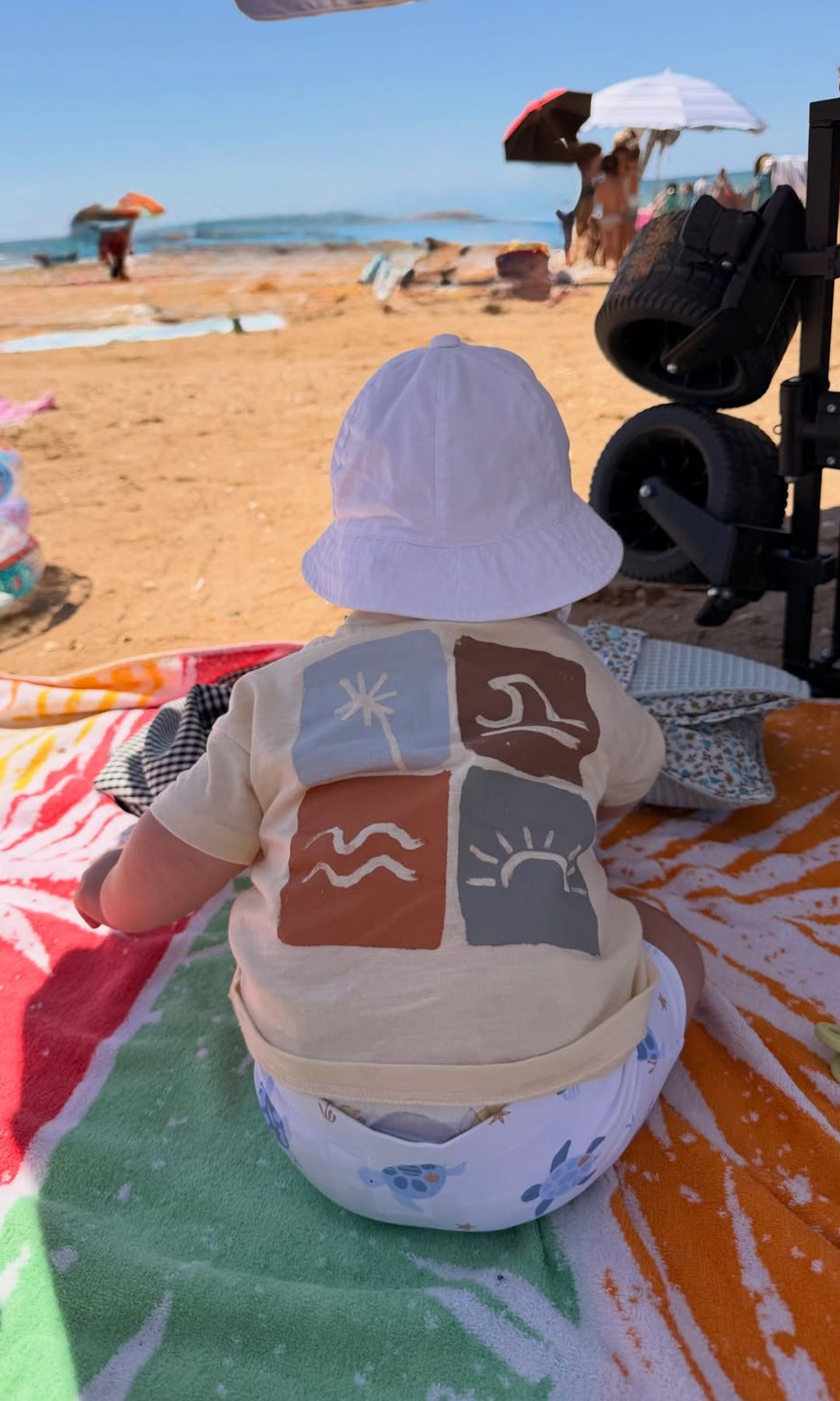 Sentado sobre una colorida toalla y contemplando la playa de espaldas, Marcos demuestra que, con apenas cinco meses, ya es un veraneante más de la familia