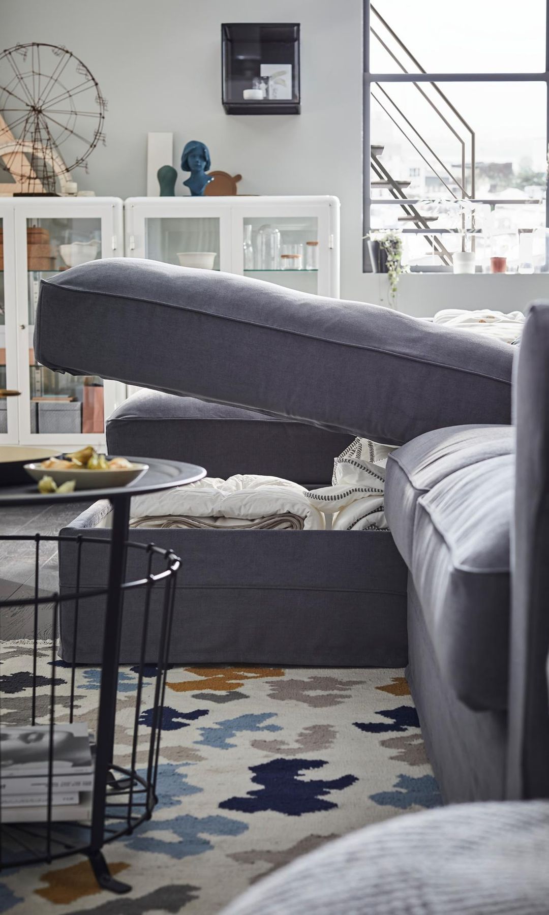 Sofá con arcón de IKEA en color gris, mesa de centro negra con cesta debajo