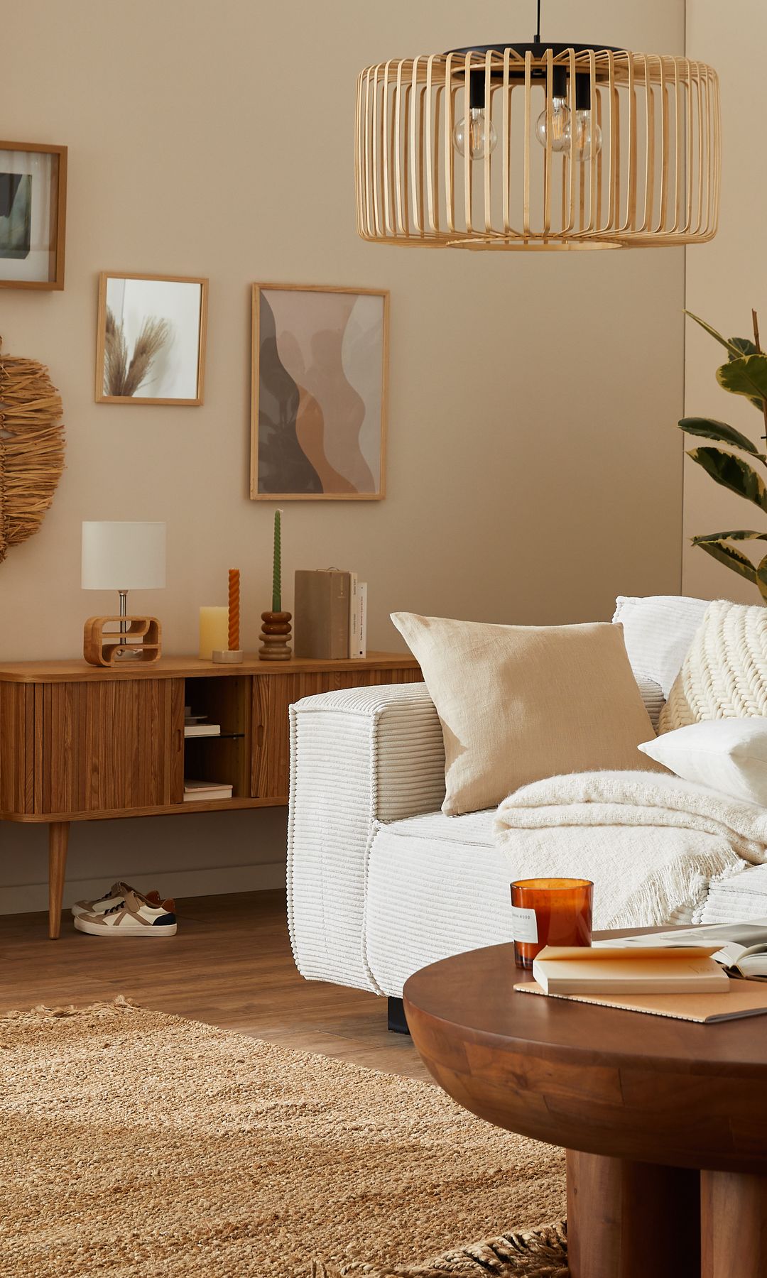 Salón con sofá blanco, alfombra de fibras vegetales, aparador de madera, lámpara de fibras vegetales, lámpara de sobremesa, cuadros en la pared, cortinas beiges