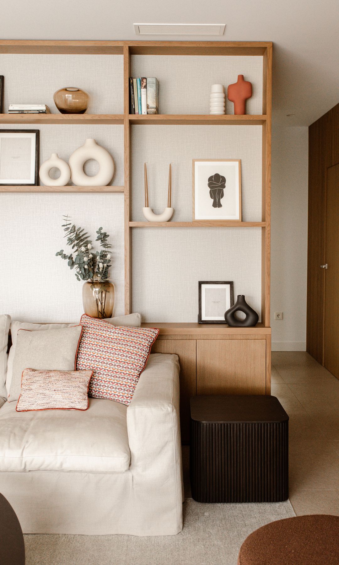 Salón con cojines y estantería de madera