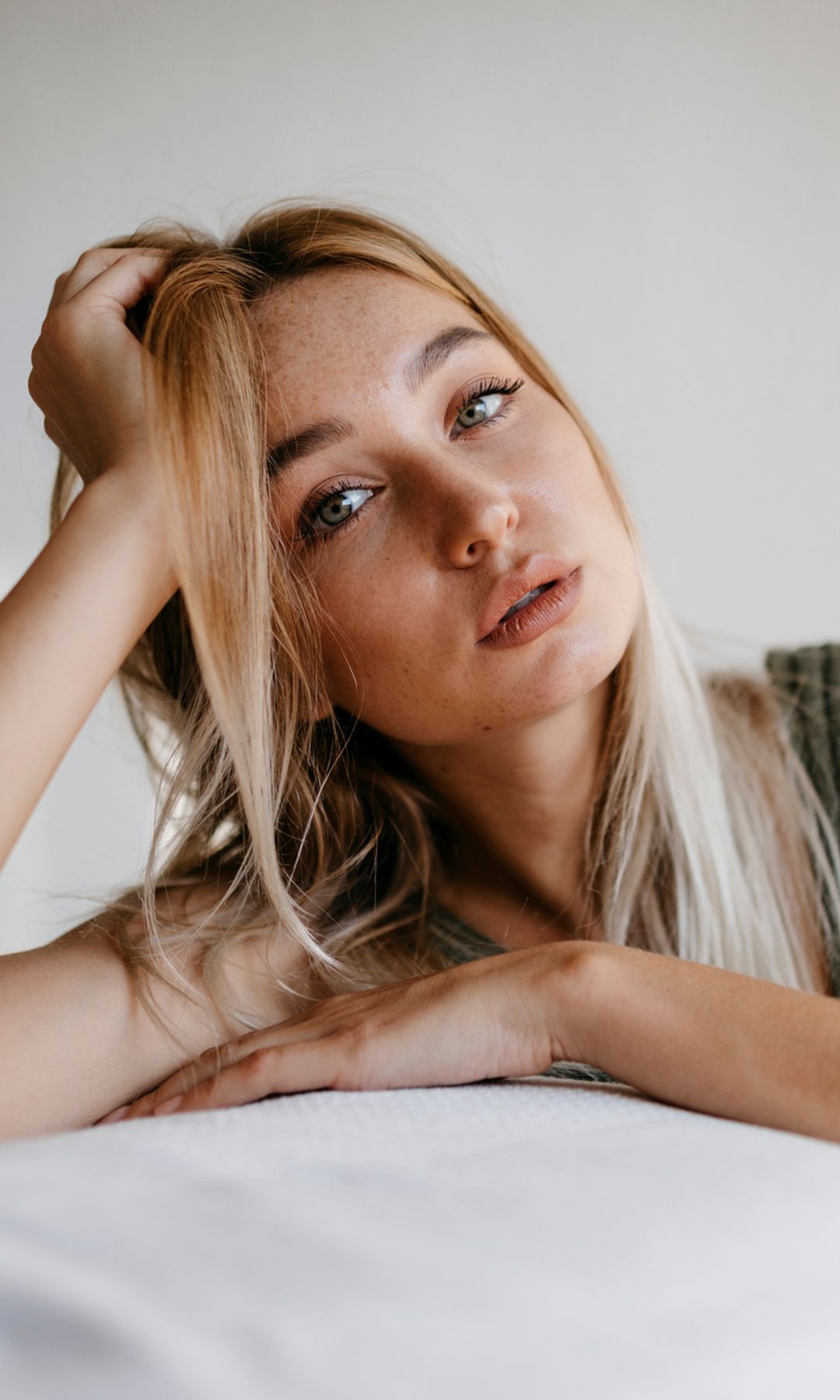 Mujer apoyada en los pies de la cama con el rostro serio