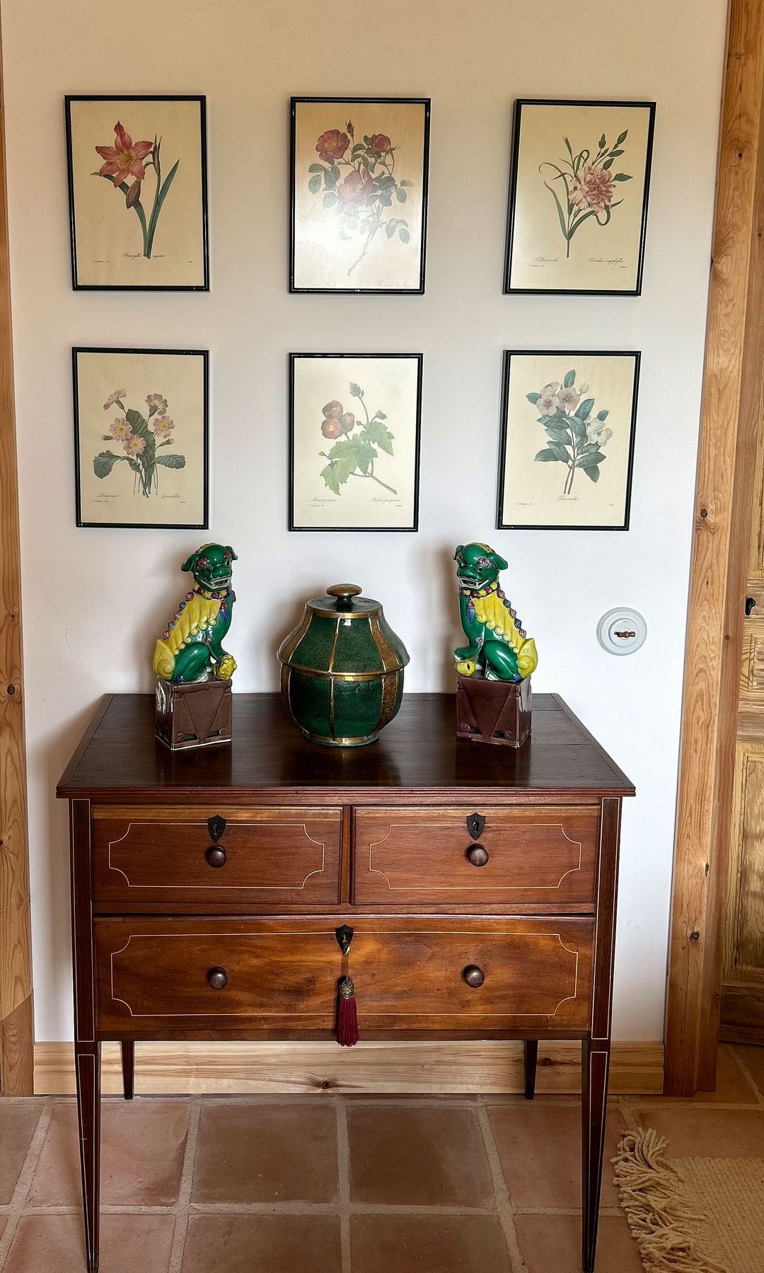 Cómoda de madera que perteneció a mi abuela materna e ilustraciones de flores colgadas en la pared. Las figuras de porcelana de leones estaban en el salón de la casa de mis padres.