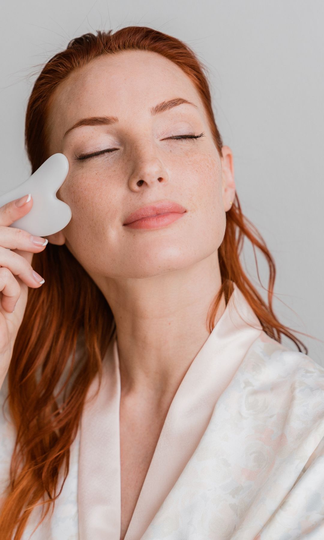 Una mujer relajada pasándose el gua sha