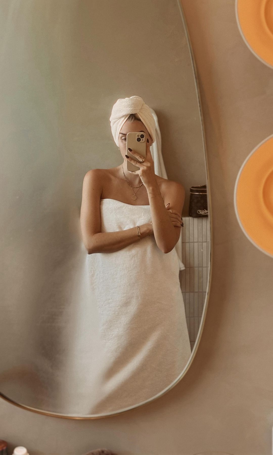 Mujer envuelta en una toalla se hace una foto frente al espejo del baño