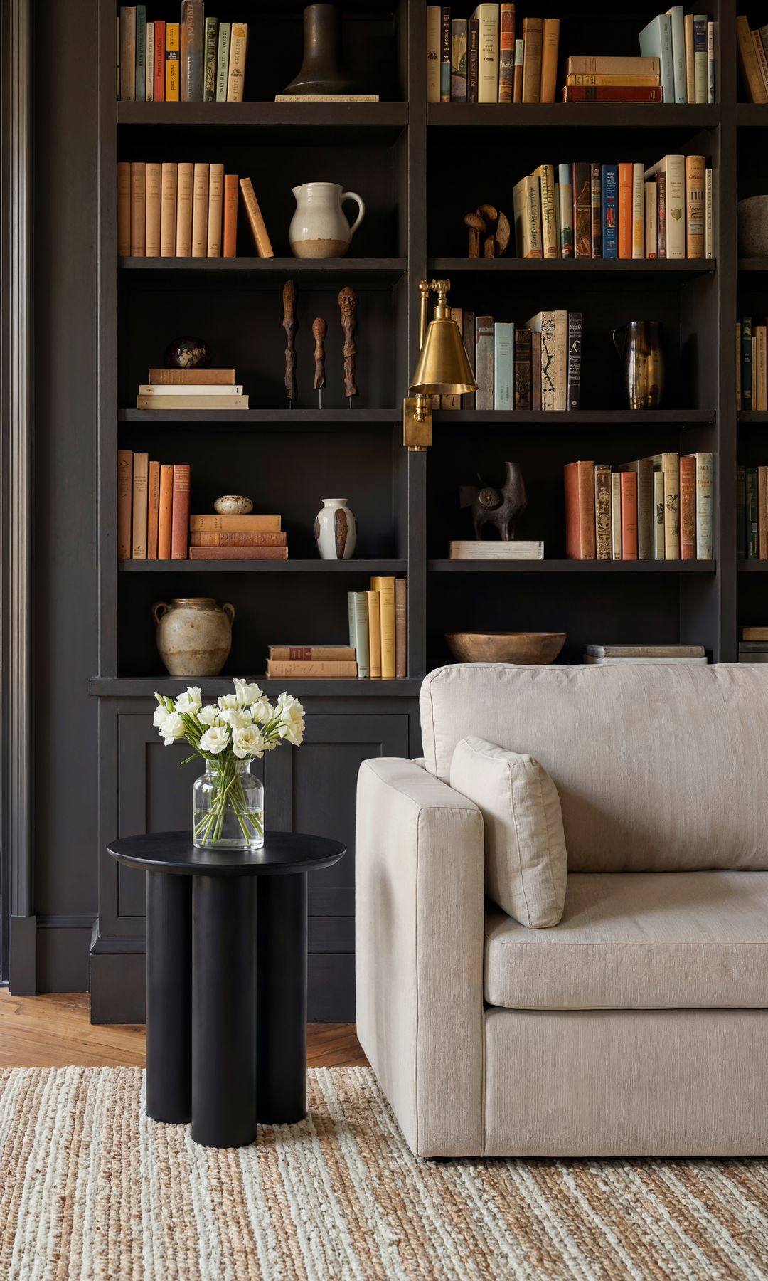 Salón con salida al porche, con librería de suelo a techo negra, sofá beige, apoque de pared dorador, alfombra, mesa auxiliar negra