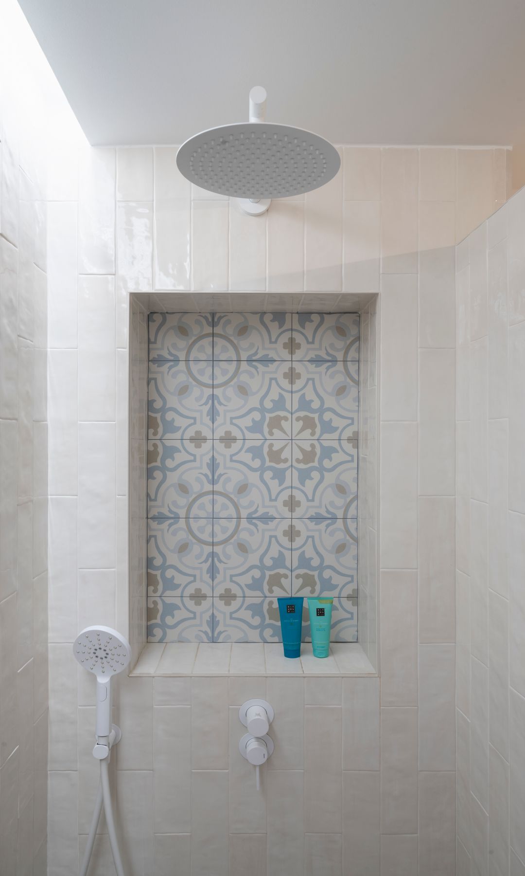 Ducha con grifería XL en el techo, teleducha de mano, hornacina con azulejos blancos y azules