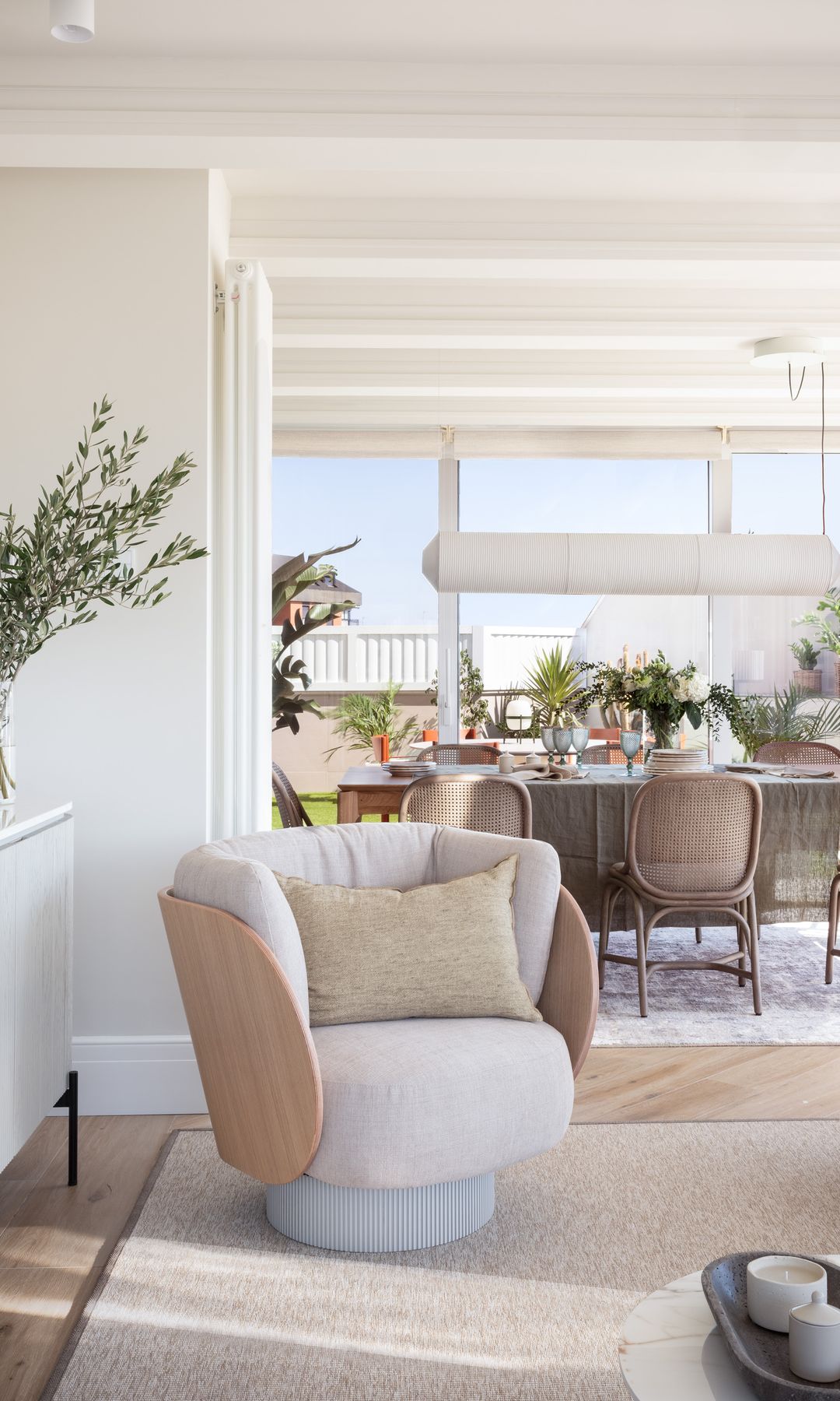 Salón comedor con alfombra de fibras vegetales, butacas blancas y aparador blanco 