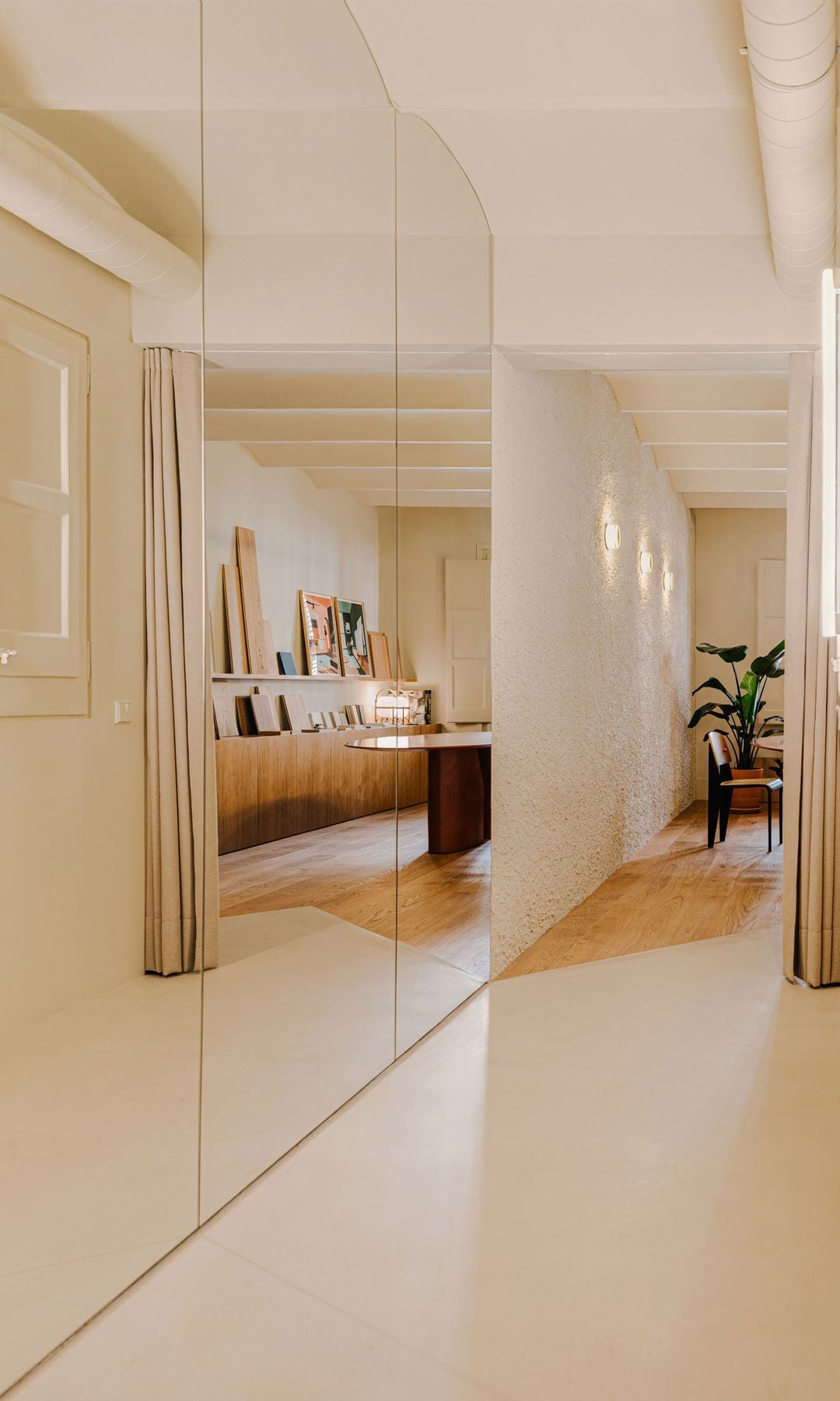 Pasillo con pared de espejo, cortinas blancas, tuberías a la vista, mueble de madera