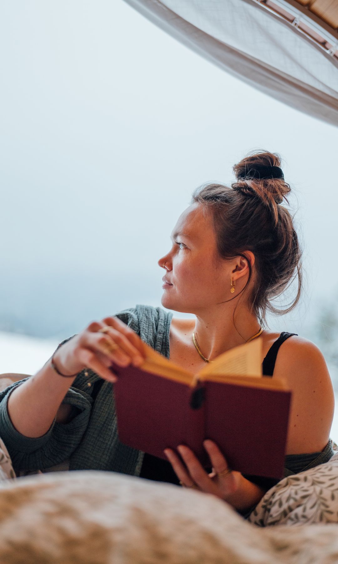 Mujer con moño en la playa leyendo un libro