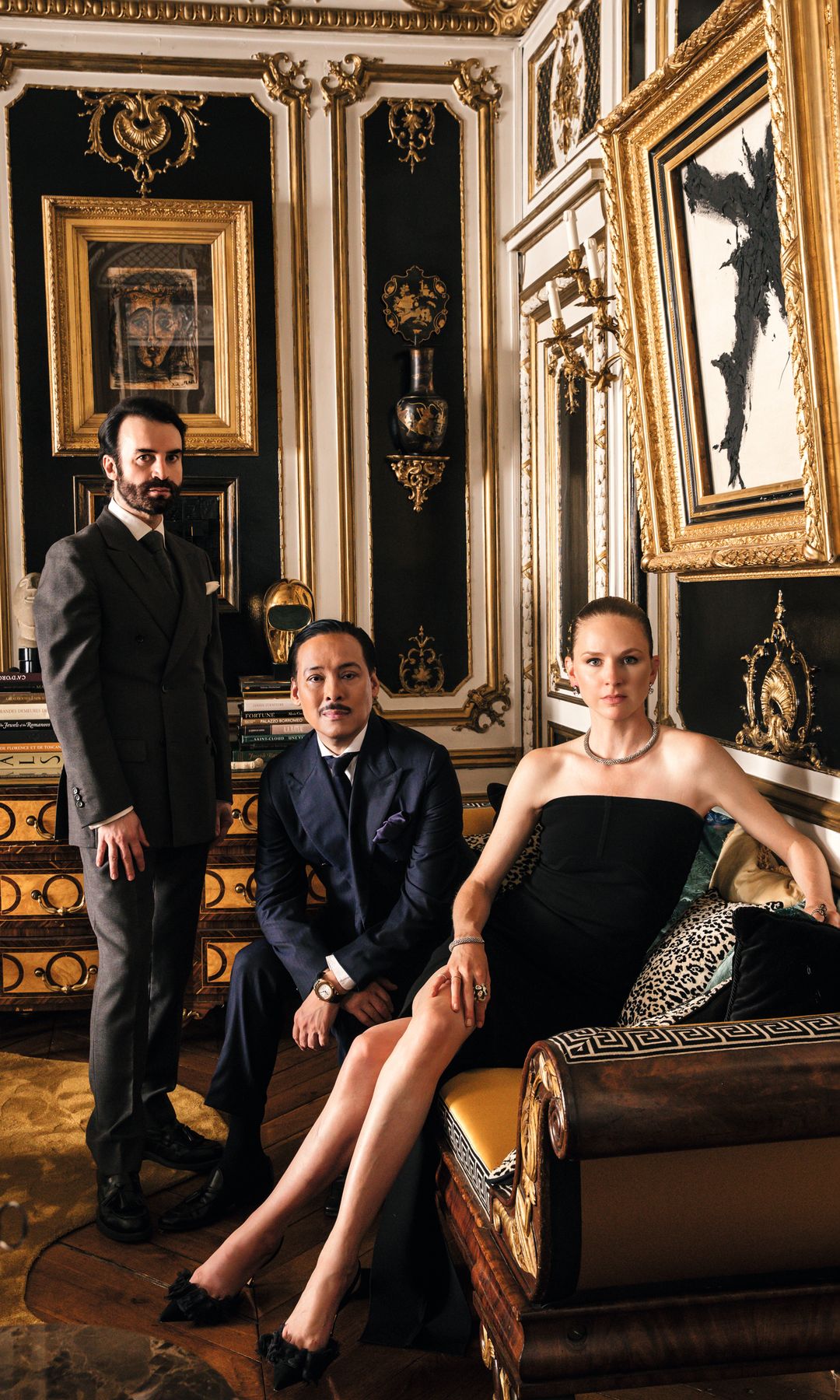 Michael y Jean-Pierre, junto a su amiga Anna Philippa Wolf, en el salón dorado de la casa. Un espacio enmarcado por molduras y "boiseries" doradas y paneles lacados en negro, en donde destaca un cuadro pintado por el propio Michael Coorengel; un banco estilo Imperio que proviene del castillo familiar de Jean-Pierre, donde están sentados, y la cómoda de estilo siglo XVII, de Maison Jansen